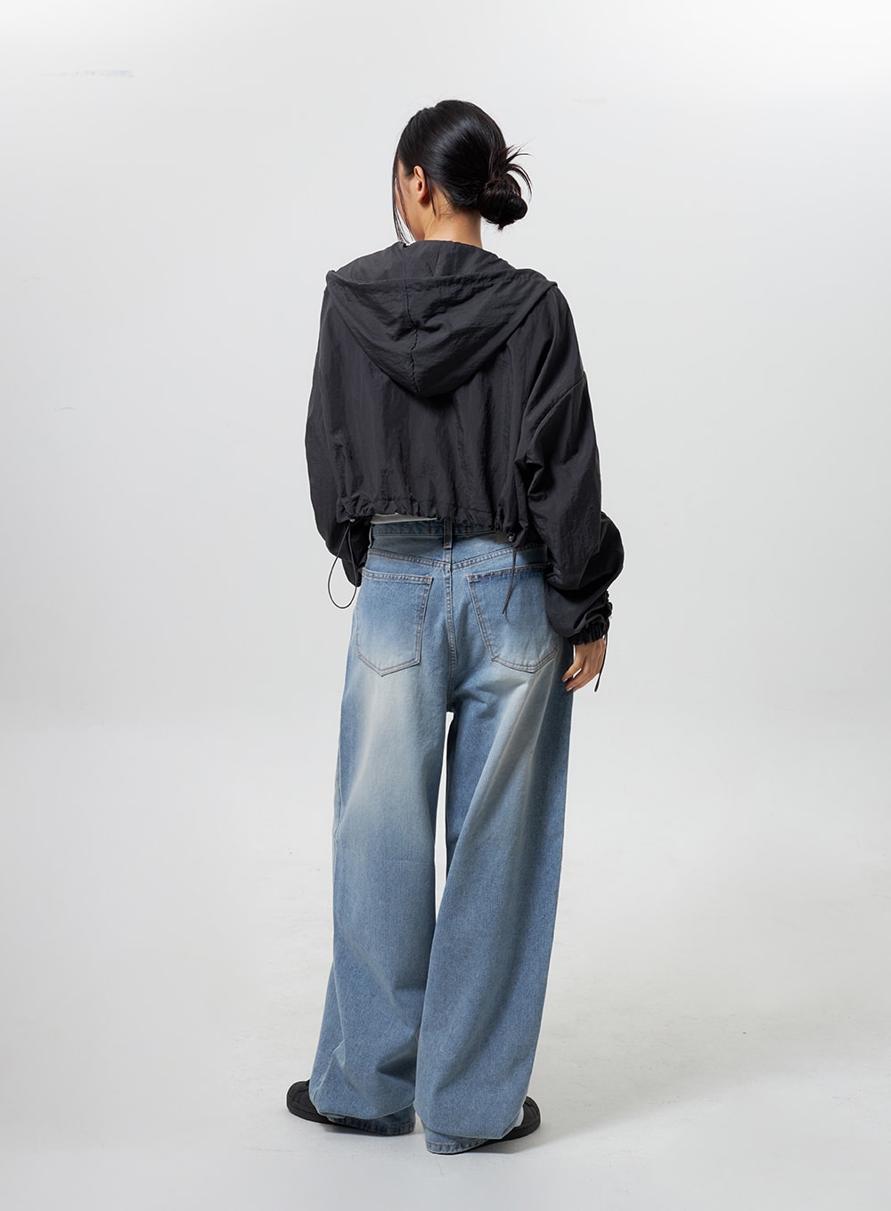 Low Rise Baggy Jeans CY324 in light blue, full-length back view on model, wide-leg baggy denim showing back pockets and faded wash, paired with black hooded cropped windbreaker.