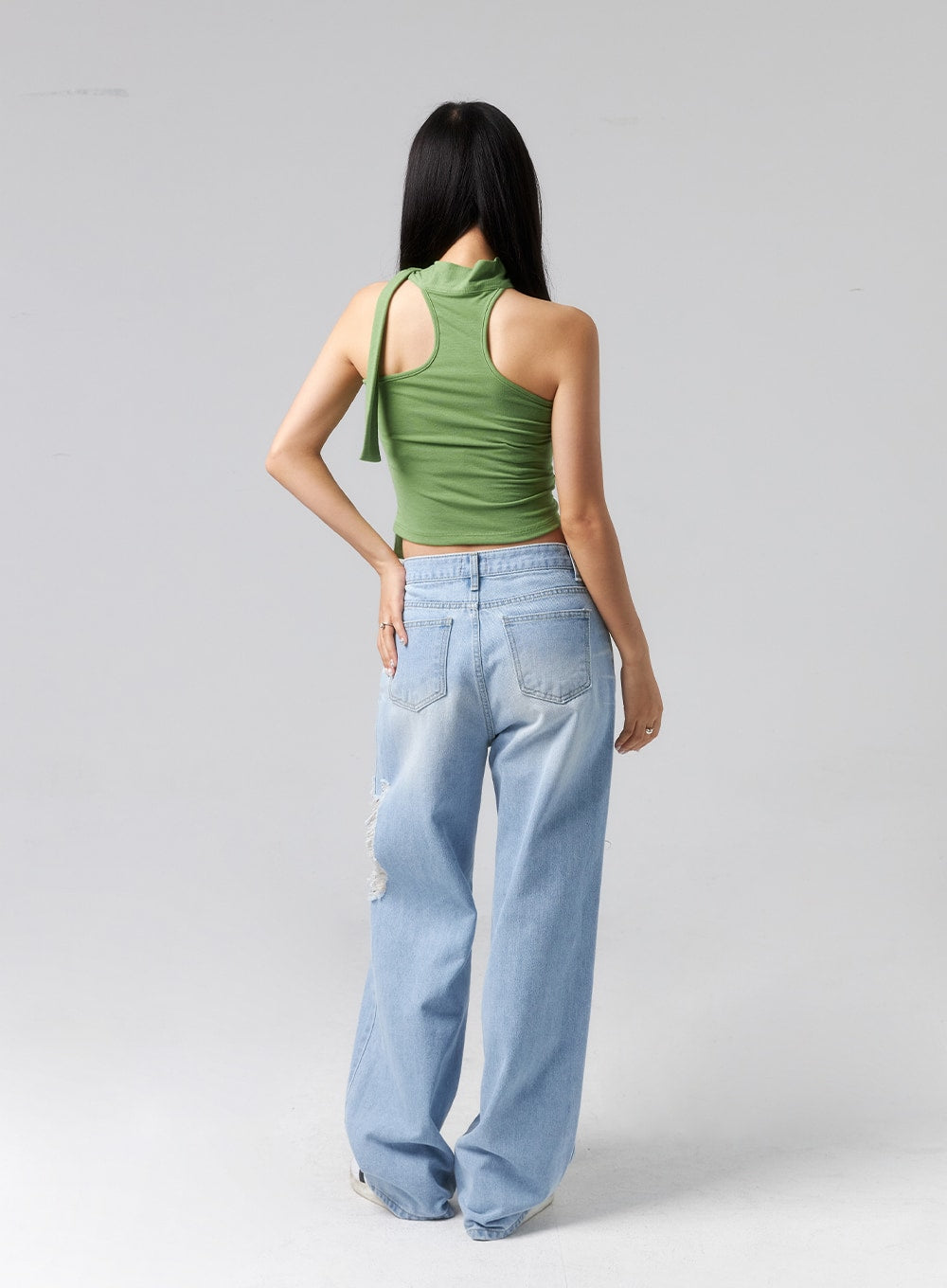 Ripped Side Jeans CL320 in light blue, full-length back view on model, wide-leg cotton denim with dual back pockets, faded wash, and destroyed rip visible at side, paired with green halter crop top.