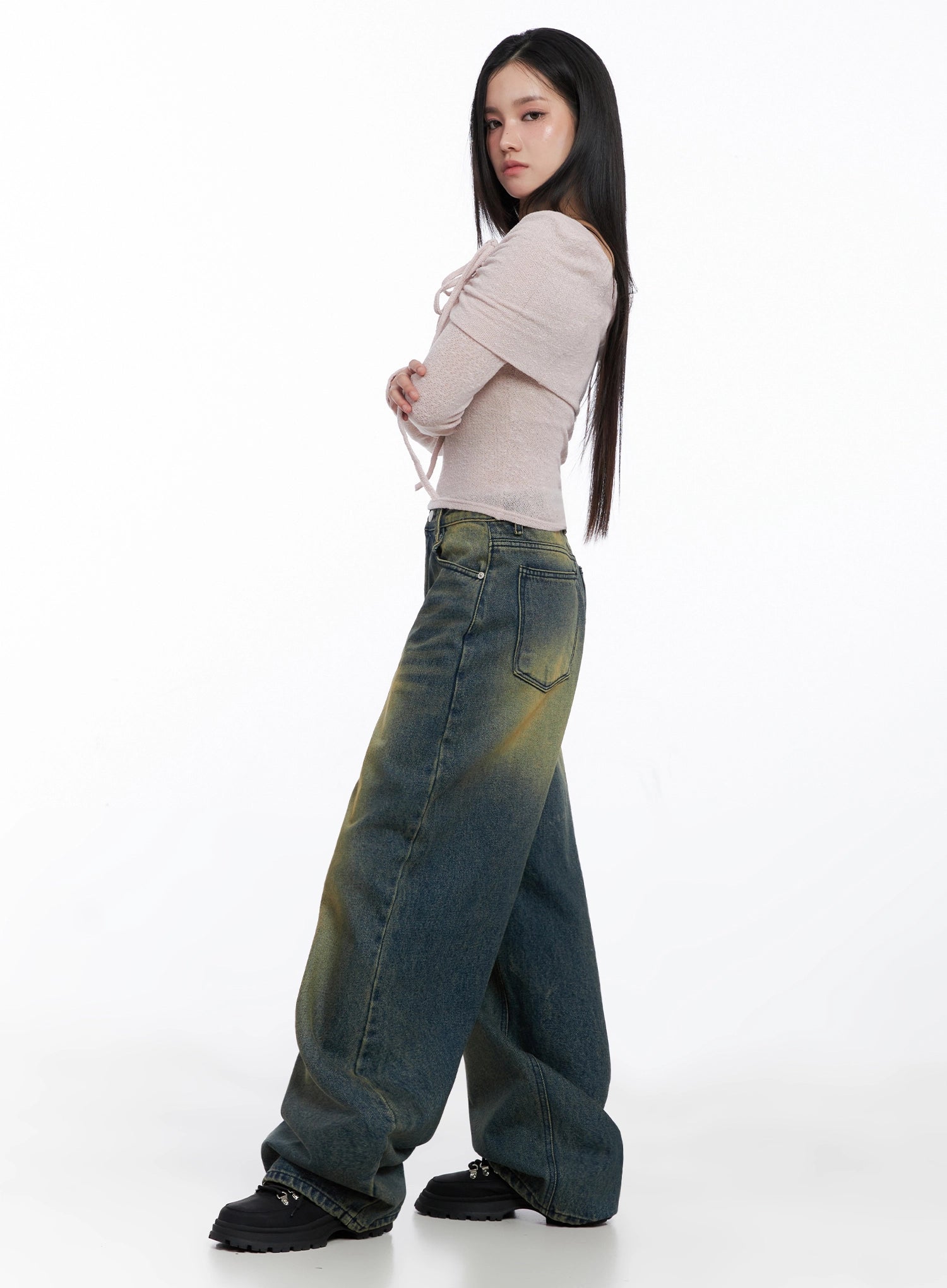 Elora Washed Baggy Jeans IS525 in dark blue, side view on model, showing back pocket and full-length baggy silhouette with yellow-green wash, paired with pink draped crop top.