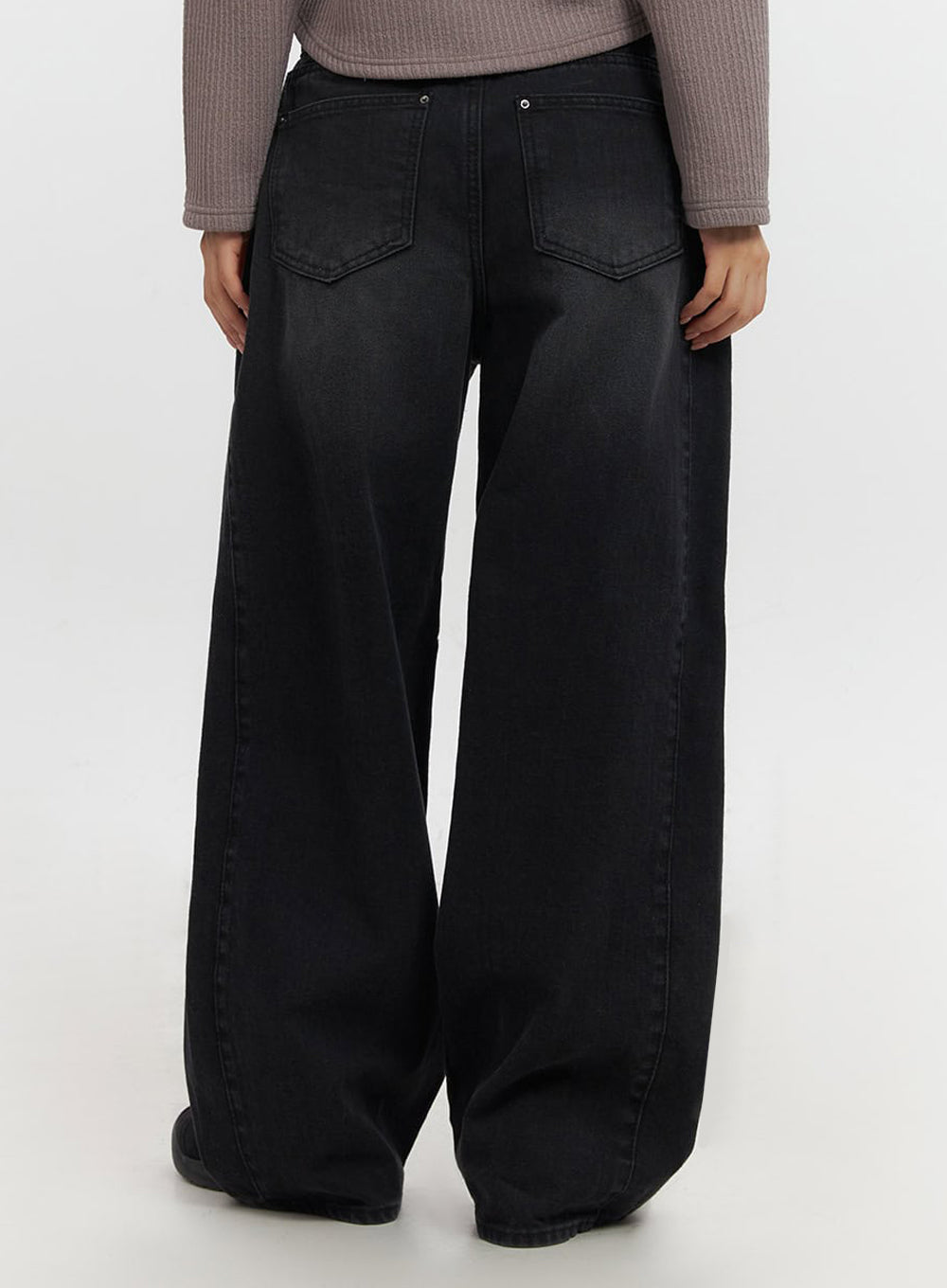 Ashly Wide-Leg Jeans IF511 in washed black, back lower-body close-up on model, angular back patch pockets with V-stitch detail, wide-leg hem pooling at floor.