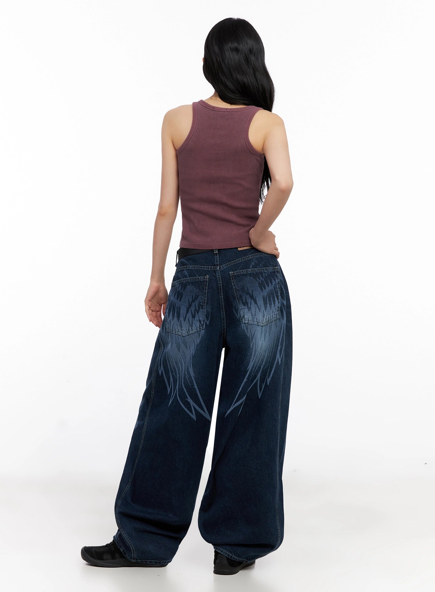 Sohee Angel Wing Print Wide-Leg Jeans IG508 in dark blue, full back view on model, angel wing print across back yoke and legs, wide-leg washed denim, styled with mauve ribbed tank and black sneakers.