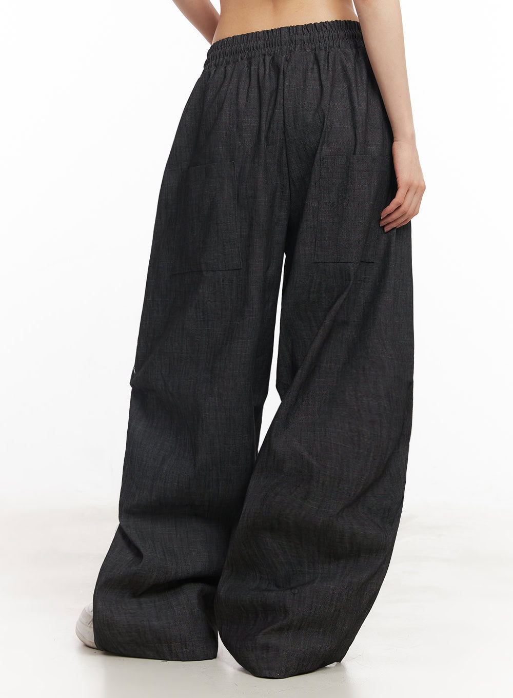 Pintuck Denim Sweatpants IY529 in black, back three-quarter view on model, showing rear patch pockets, elastic banded waist, and voluminous wide-fit cotton denim hem.