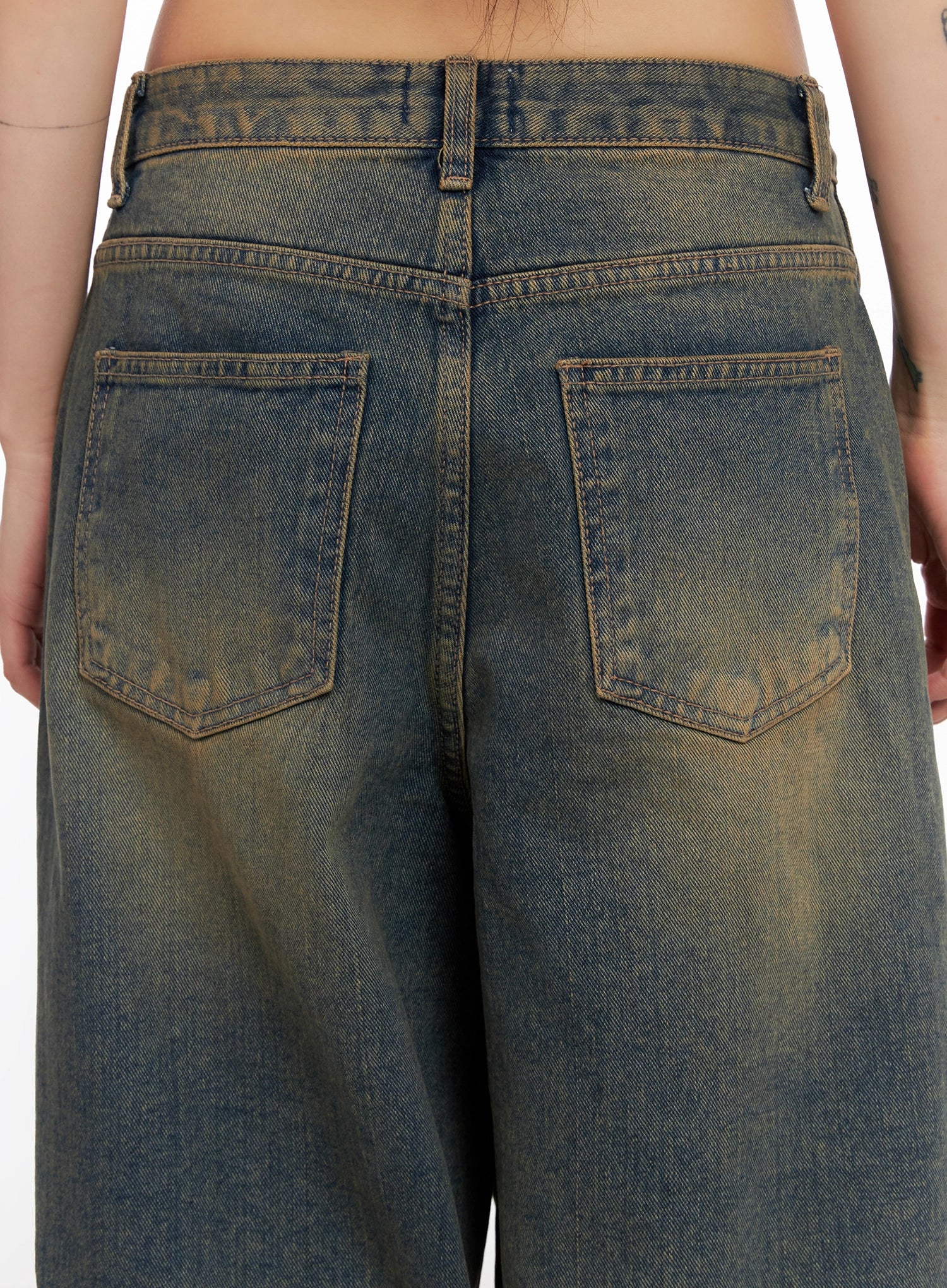 Minju Vintage Washed Baggy Jeans IS508 in dark blue, back waist close-up on model, detailing two patch back pockets, back yoke seam, belt loops, and yellow-tinted vintage washed denim.