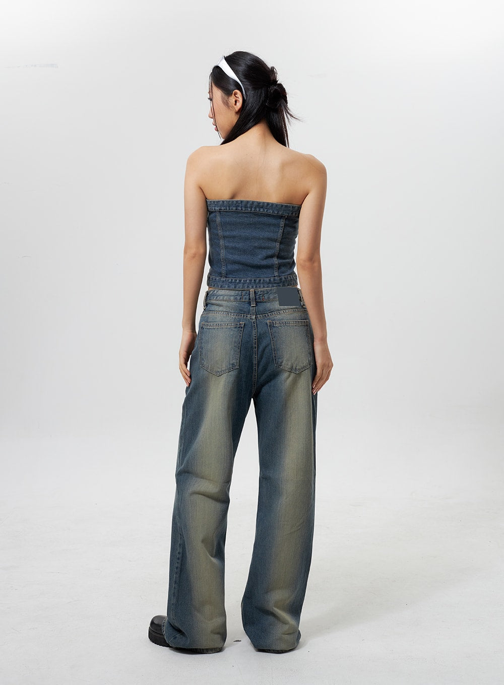Low Rise Wide Leg Jeans CY323 in vintage blue, full back view on model, rear patch pockets with stitching detail, low-rise waistband, wide-leg silhouette with yellow fade wash, paired with denim tube top.