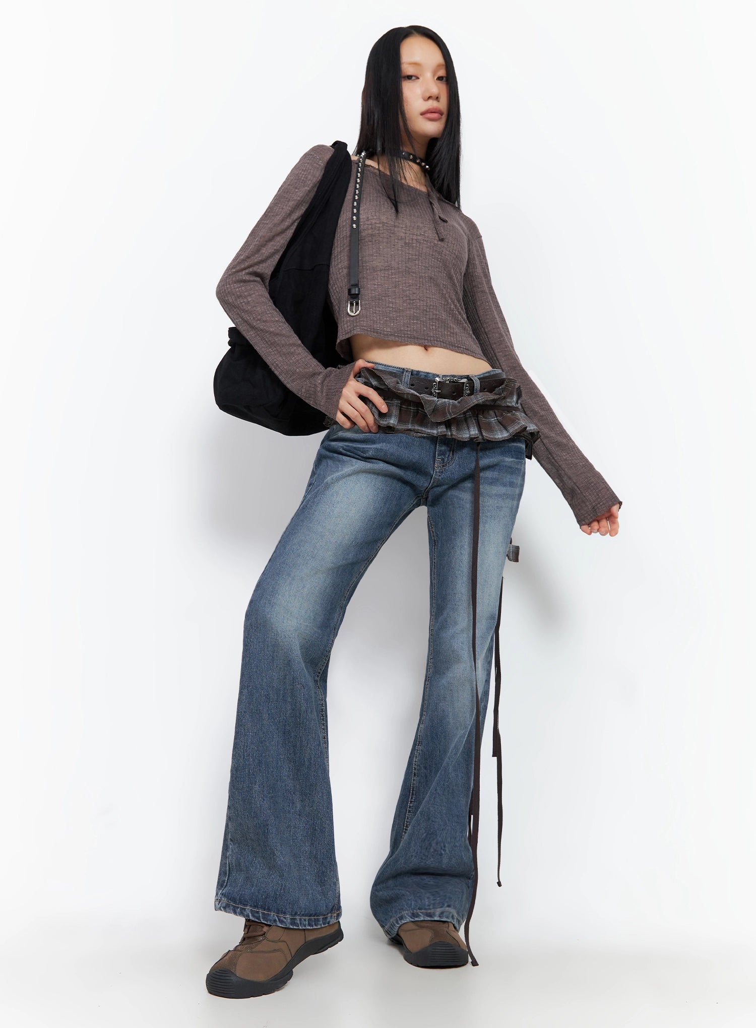 Myra Washed Bootcut Jeans IO516 in dark blue, full-body front editorial on model, styled with brown waffle crop top, plaid wrap skirt belt, black tote, and chunky brown sneakers.