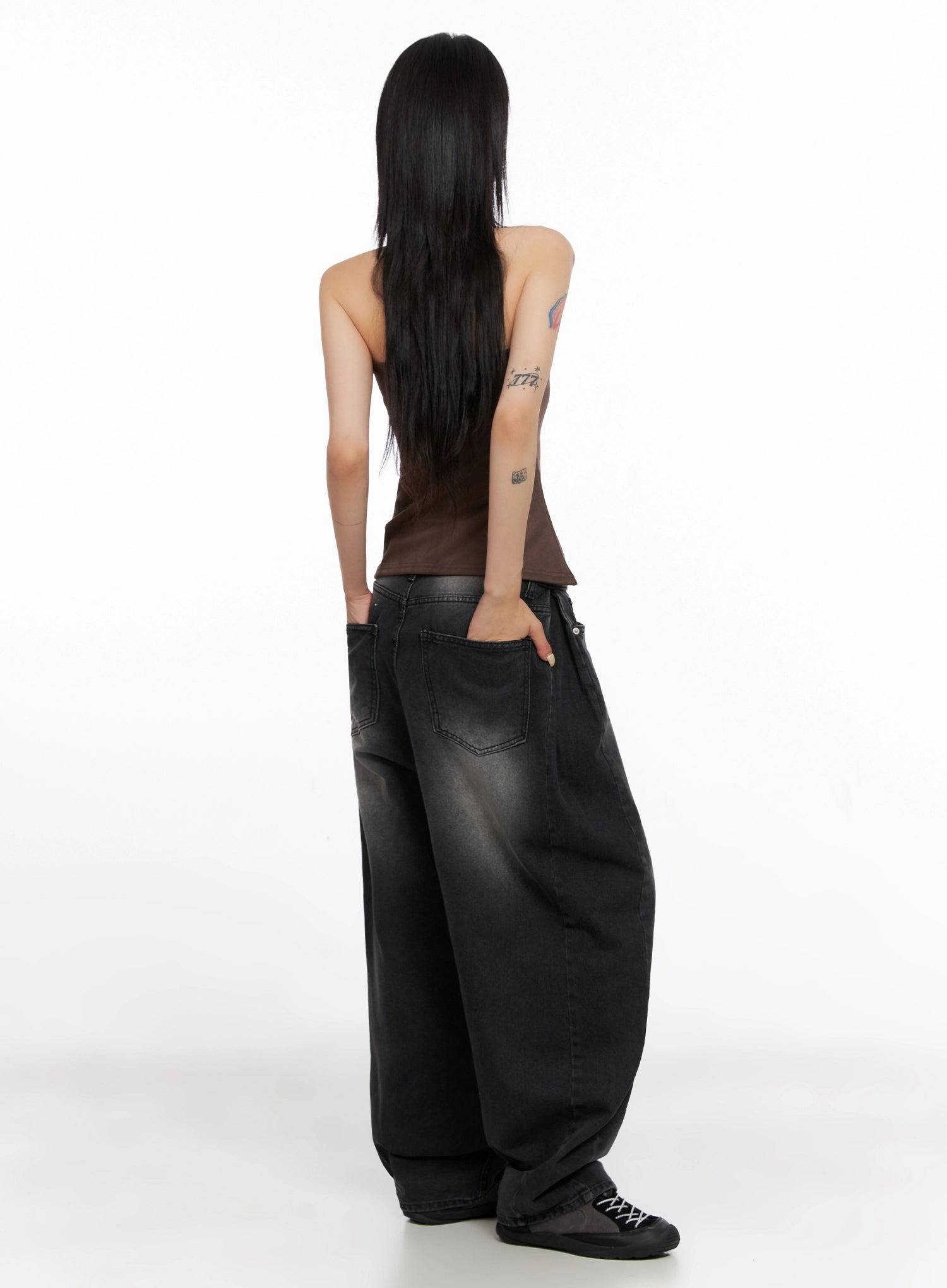 Ayra Dark Washed Baggy Jeans IS508 in dark grey, back view on model, showing rear patch pockets with contrast stitching, faded dark wash, and oversized baggy leg silhouette, styled with brown tube top.