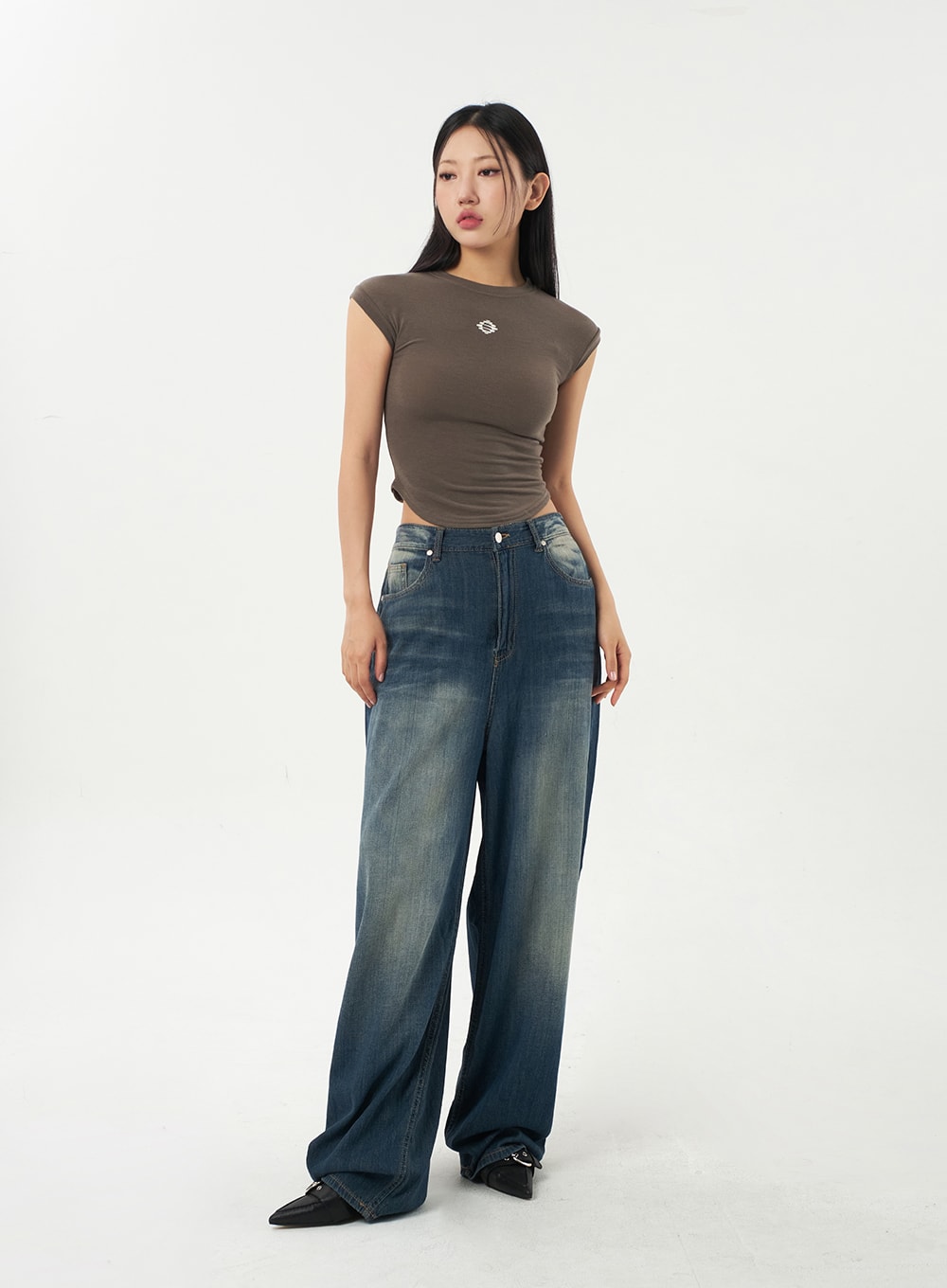 Baggy Low Rise Jeans CA326 in dark blue, angled front full-body shot on model, low-rise wide-fit denim with warm yellow fading at hips, silver button hardware, casual styling.