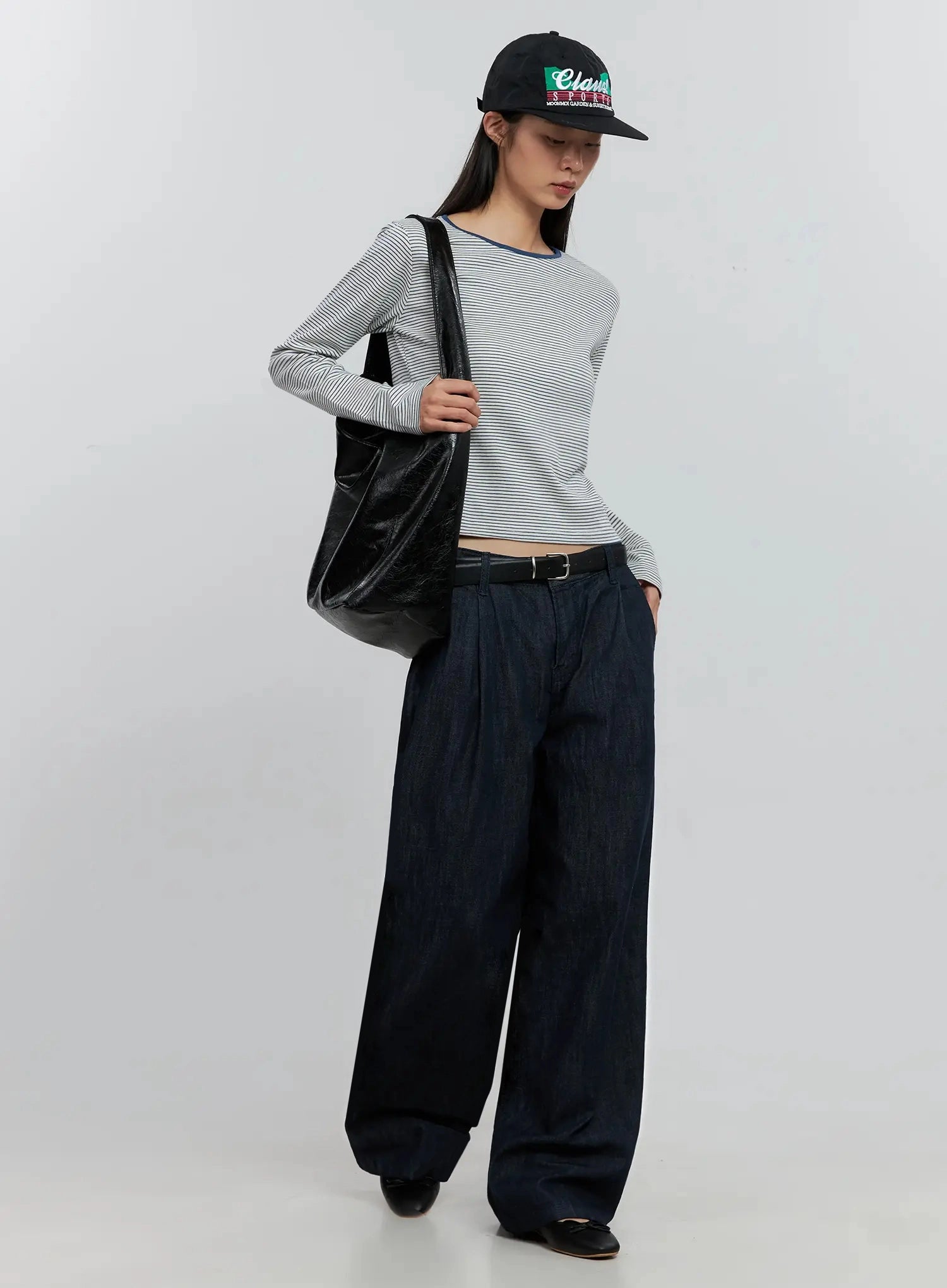 Elio Pintuck Wide-Leg Jeans IS516 in dark indigo, full-length styled shot on model with black belt, black tote bag and cap, pintuck wide-leg cotton denim in casual look.