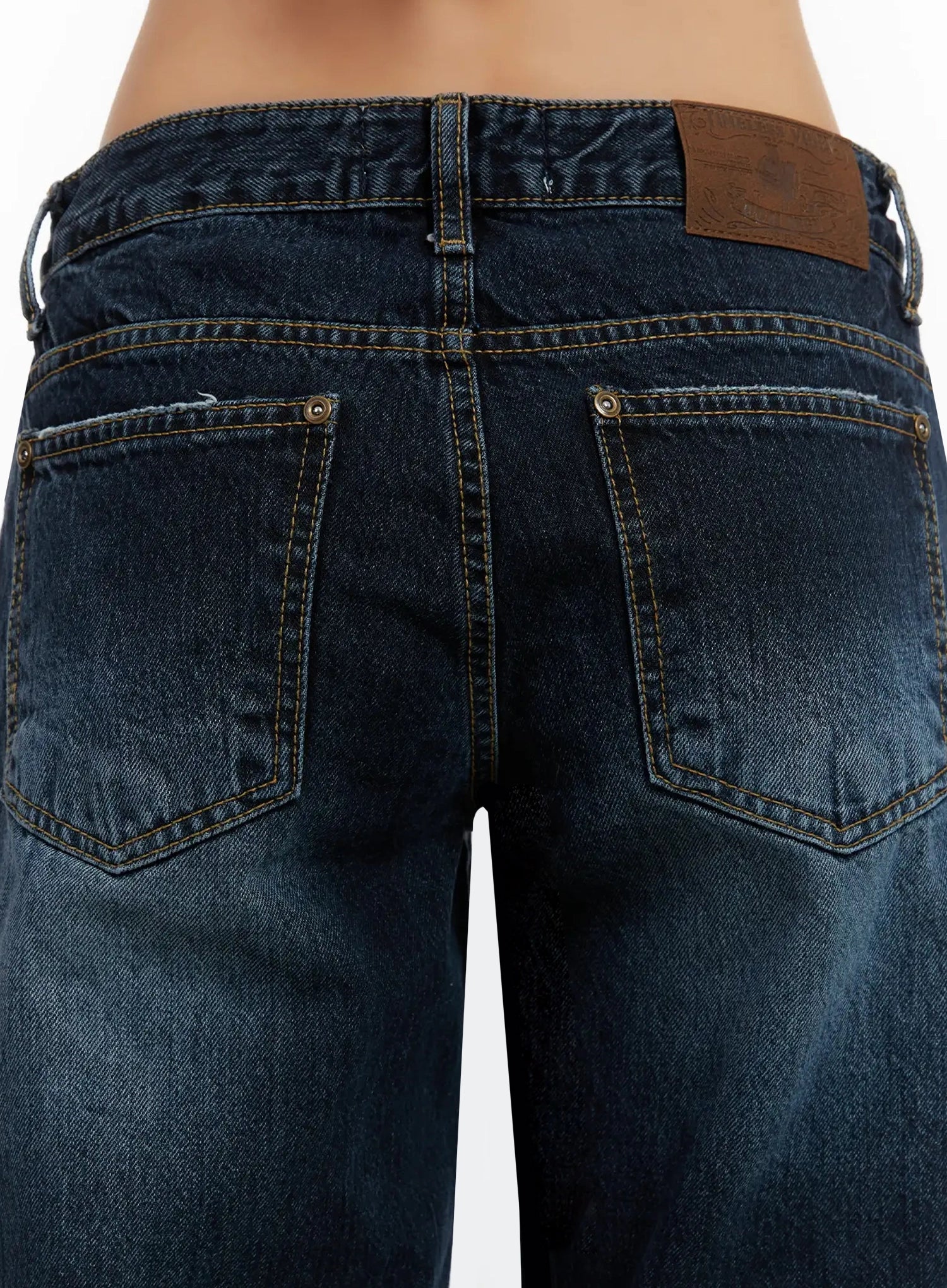 Aimee Low Rise Wide Leg Jeans ID525 in dark blue wash, macro close-up of back waistband area, dual back pockets with contrast topstitching, rivets, leather patch label, and washed denim texture.