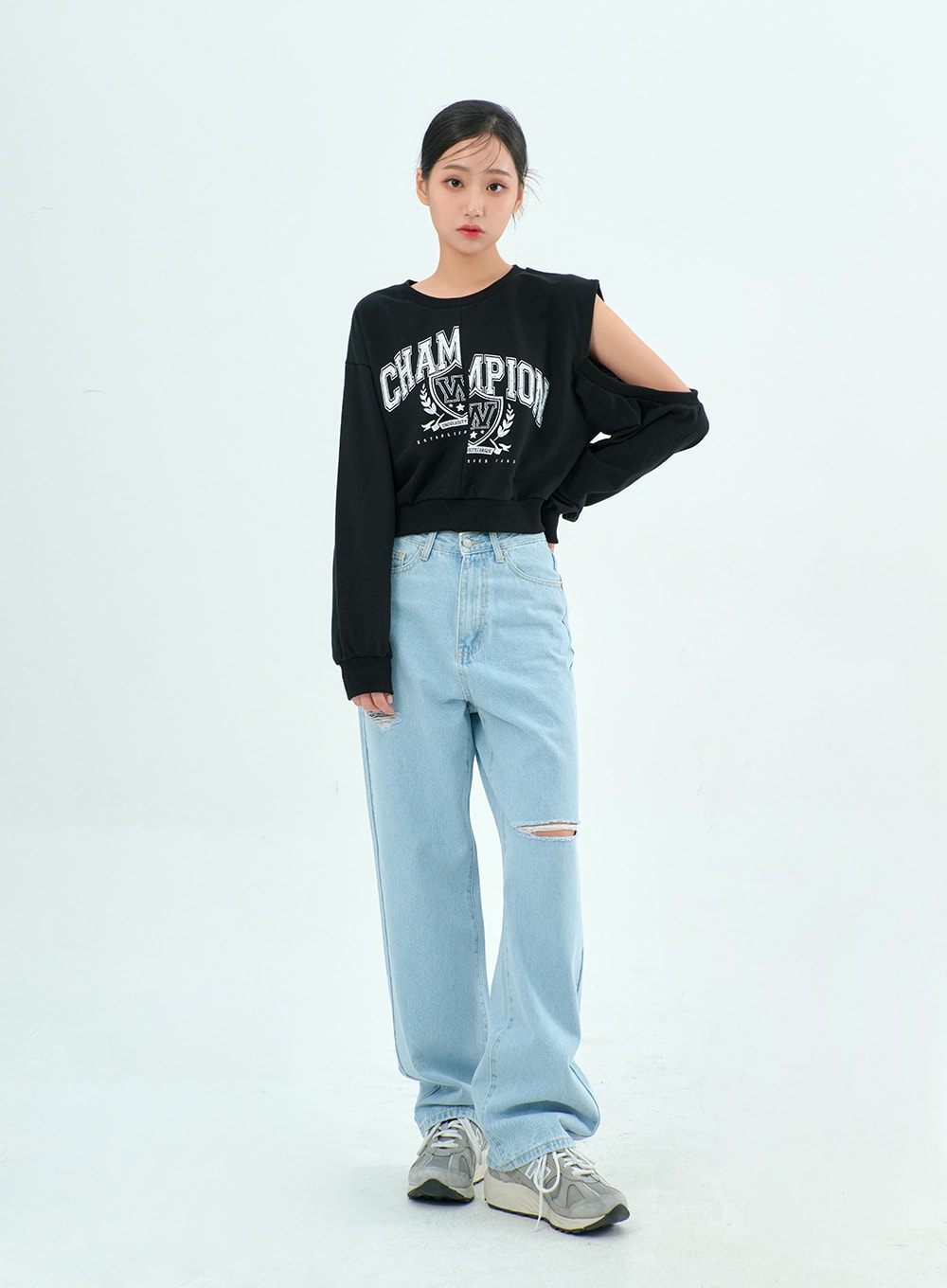 Ripped Basic Jeans BA328 in light blue, full-length front view on model standing straight, wide-fit cotton denim with knee rip, styled with black graphic crop sweatshirt and grey sneakers.