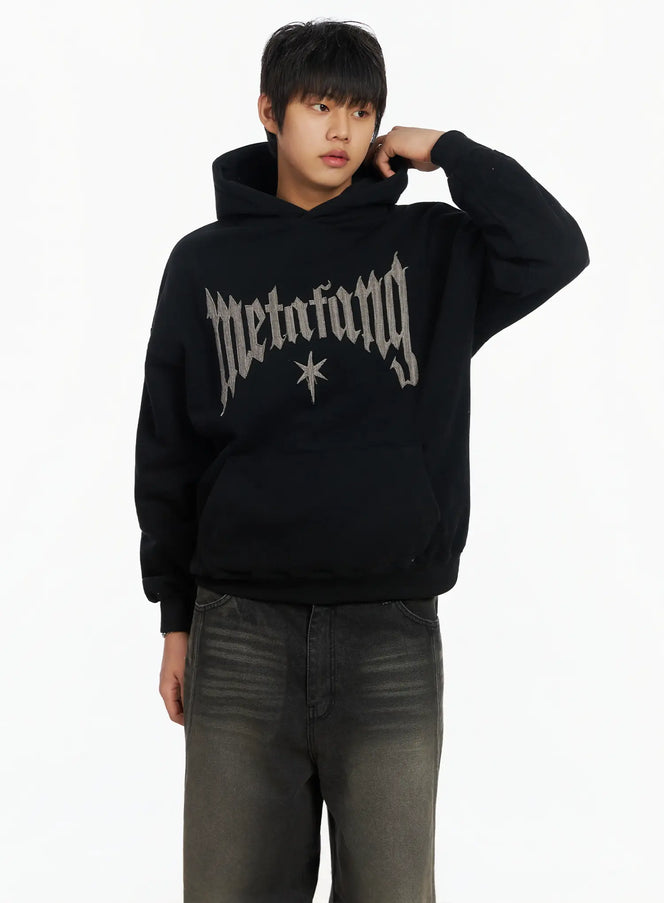 LEWKIN Men's Patch Stitch Fleece Hoodie IF503 in Black, front three-quarter view on model, oversized fleece hoodie with gothic patch-stitch lettering and star motif, paired with dark wash jeans.