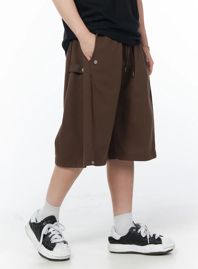 LEWKIN Men's Casual Snap Button Bermuda Shorts (Dark Brown) IY522 in dark brown, angled side view on model, wide-leg bermuda length with snap buttons on hem and side pocket, paired with black tee and sneakers.