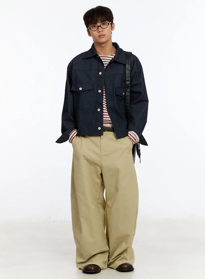 Men's Beige Wide Leg Pants IM530 in beige, full-body front on male model, styled with dark denim cropped jacket, striped tee, braided belt, and black crossbody bag.