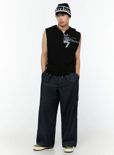 Men's Wide Leg Jeans (Dark Blue) IU516 in dark blue, full front view on male model, drawstring elastic waist, stud cross accent on leg, styled with black graphic sleeveless hoodie and beanie.