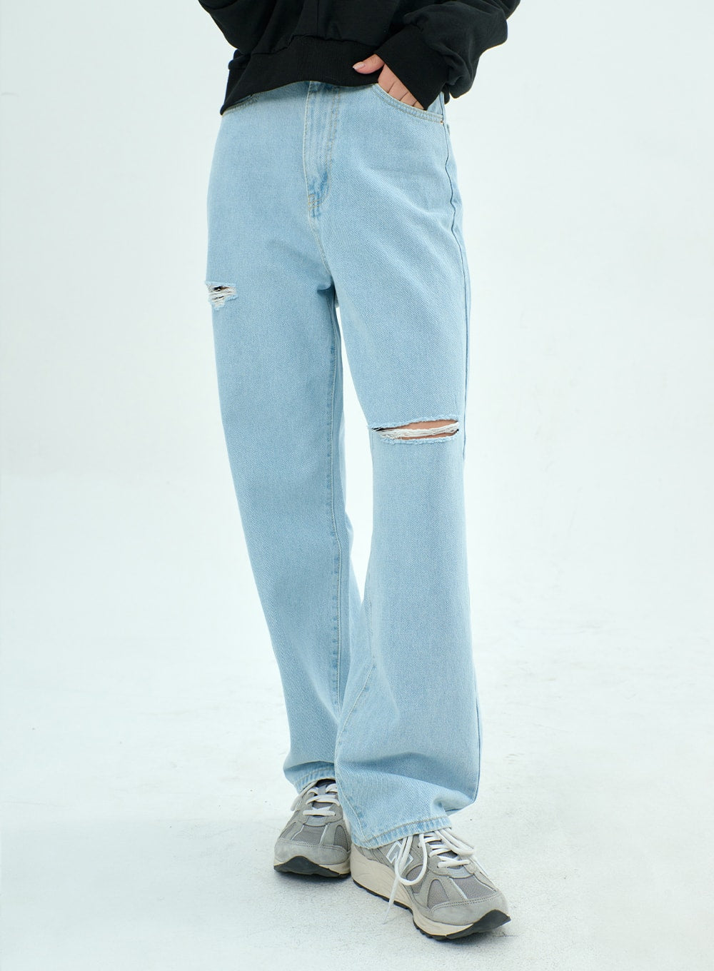 LEWKIN Ripped Basic Jeans BA328 in light blue, front three-quarter view on model, wide-fit cotton denim with destroyed knee slits, paired with black sweatshirt and grey sneakers.