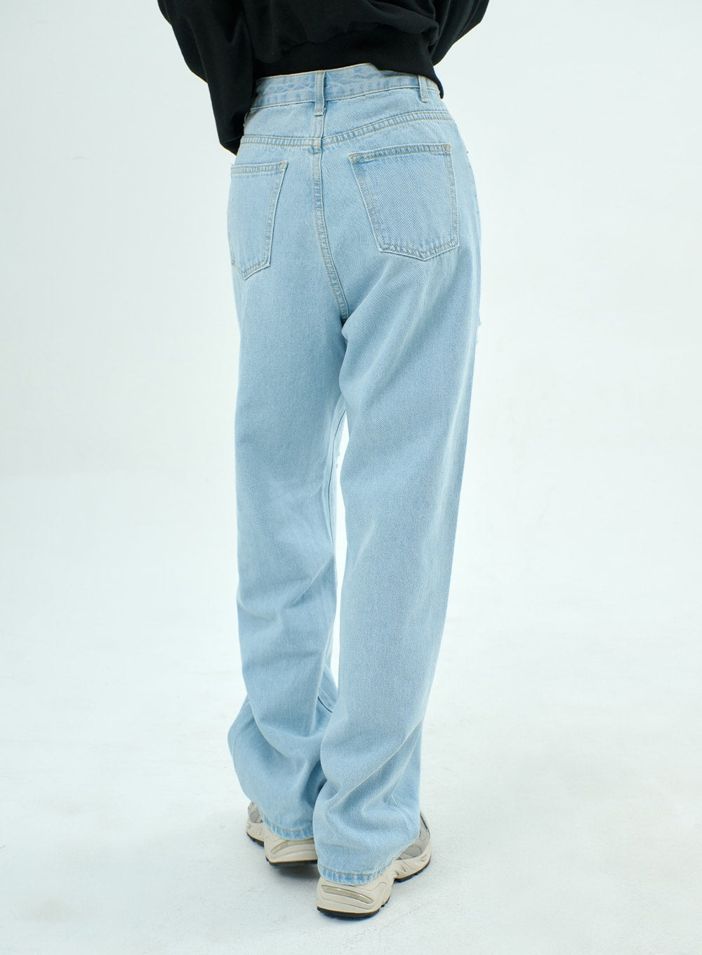 Ripped Basic Jeans BA328 in light blue, back view on model, showing dual patch pockets and relaxed wide-fit denim cut, paired with black sweatshirt and sneakers.