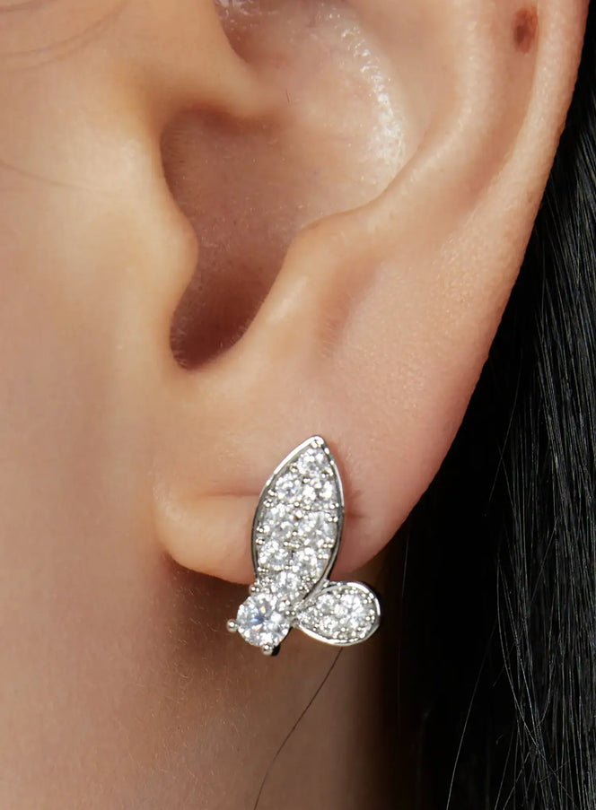 LEWKIN Emerson Earring IU503 in silver, close-up worn on model's ear, butterfly stud with pavé crystal wings and bead accents, feminine everyday style.