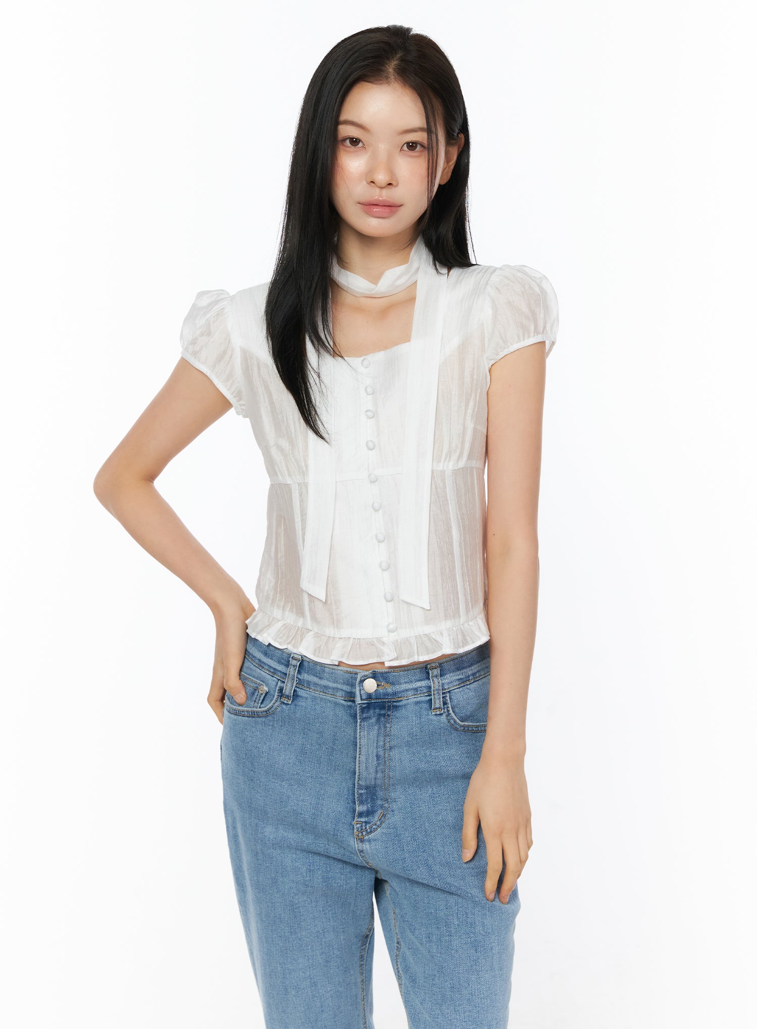 Puff Sleeve Shirred Blouse with Scarf IU519 in white, front view on model with hand on hip, lightweight sheer nylon-tencel fabric with shirring and ruffled hem, scarf accent, with blue jeans.