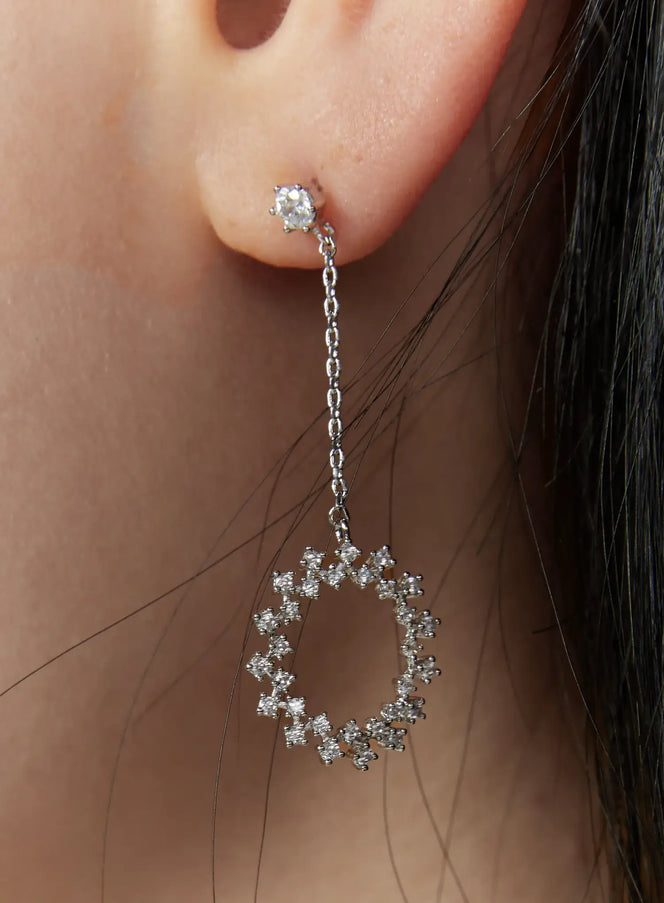 LEWKIN Erasmus Earring IU503 in silver, close-up worn on model's ear, crystal stud post with delicate chain dropping to an open oval hoop encrusted with sparkling CZ stones.