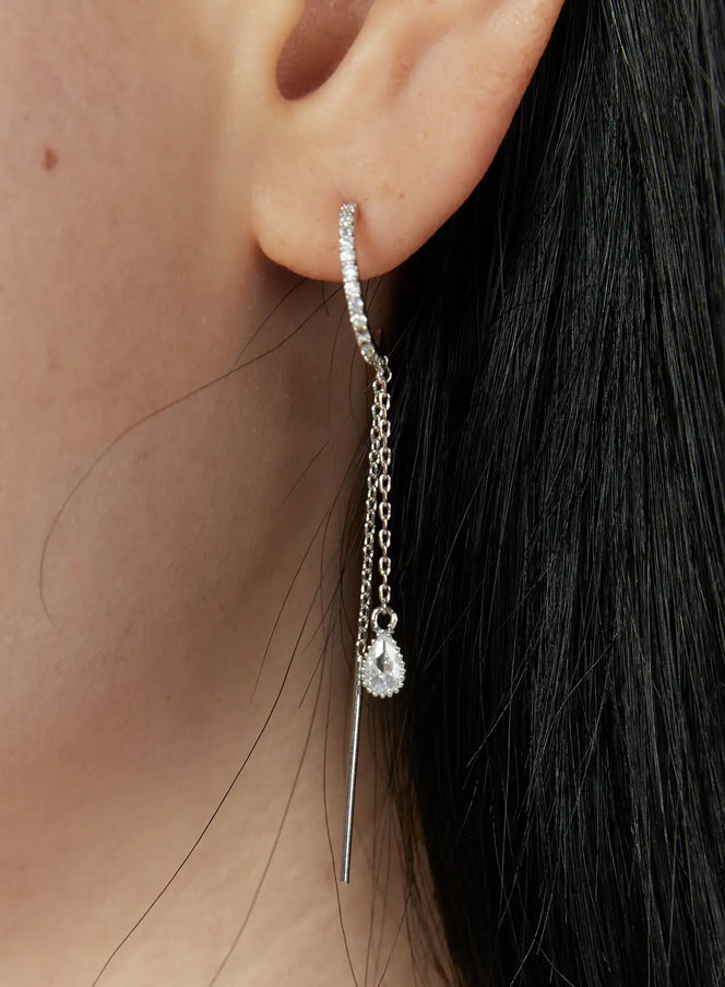 LEWKIN Gideon Earring IU503 in silver, close-up worn on model's ear, pave crystal hoop with double chain drop and teardrop CZ charm alongside slim needle bar.