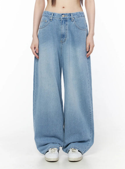 Nella Wide Leg Jeans CU519 in blue, front mid-body shot on model, light-wash denim with wide leg silhouette and generous hem pooling over white sneakers.