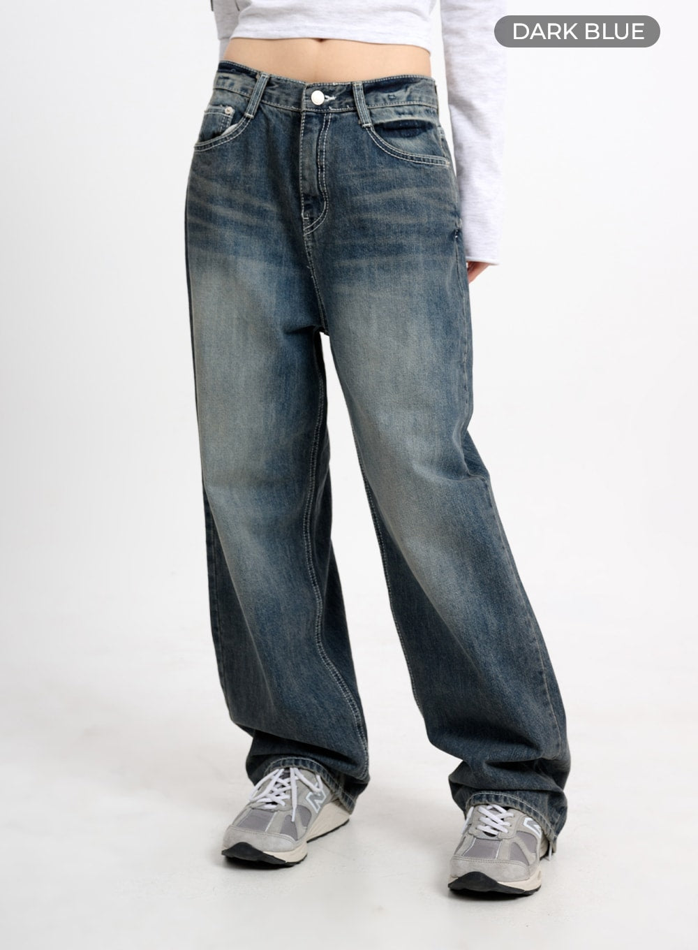 Low Waist Baggy Jeans CM415 in dark blue, front three-quarter shot with color label, wide-fit low-waist washed cotton denim, relaxed drape, paired with white crop top and sneakers.