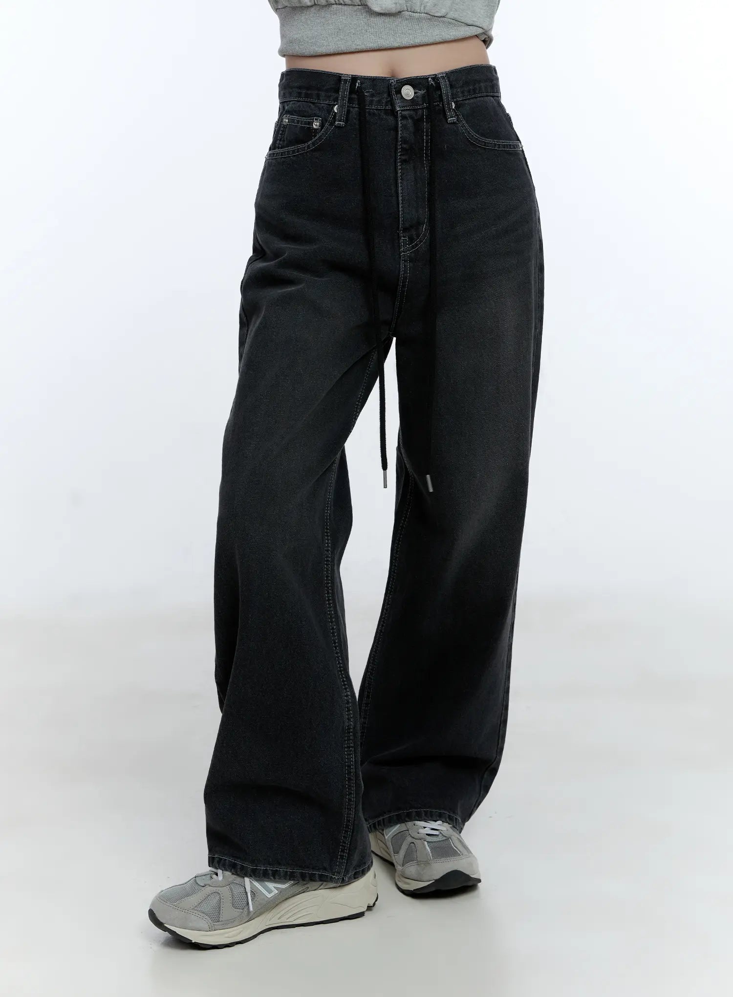 Lucinda High-Rise Wide Leg Jeans CG512 in black, front angled close-up from waist to hem on model, washed denim with high-rise waist, front pockets, drawstring cord detail, and roomy wide leg, with sneakers.