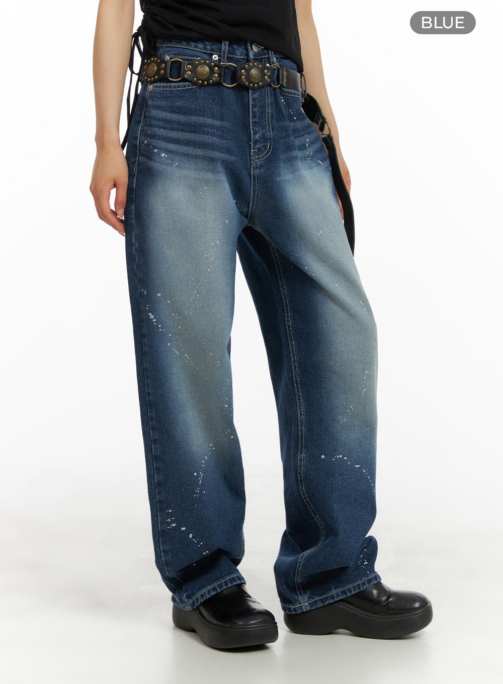 Splash Paint Baggy Jeans CA408 in blue, angled side-front view on model, wide-leg silhouette with paint splatter and washed fade, worn with studded leather belt and black platforms.