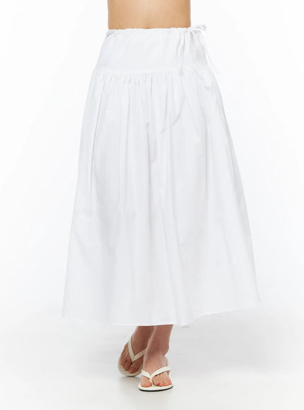 Basic Ribbon Maxi Skirt CU522 in white, front waist-to-hem shot on model, gathered tiered cotton A-line skirt with elastic ribbon tie waistband, worn with white flip-flops.