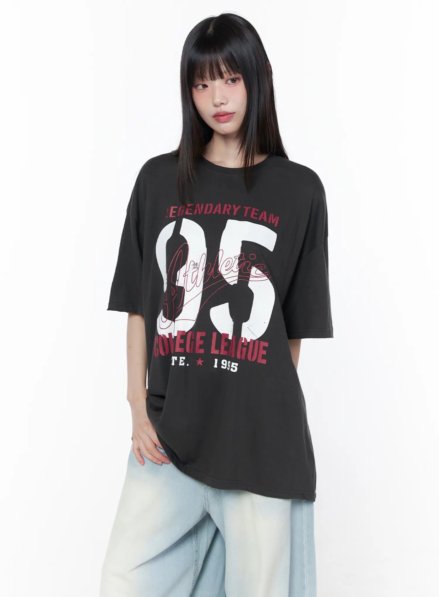 Oversized Graphic Tee CU519 in dark gray, front upper-body shot on model, showcasing crew neckline, short drop-shoulder sleeves, and full collegiate 95 graphic, paired with wide-leg jeans.