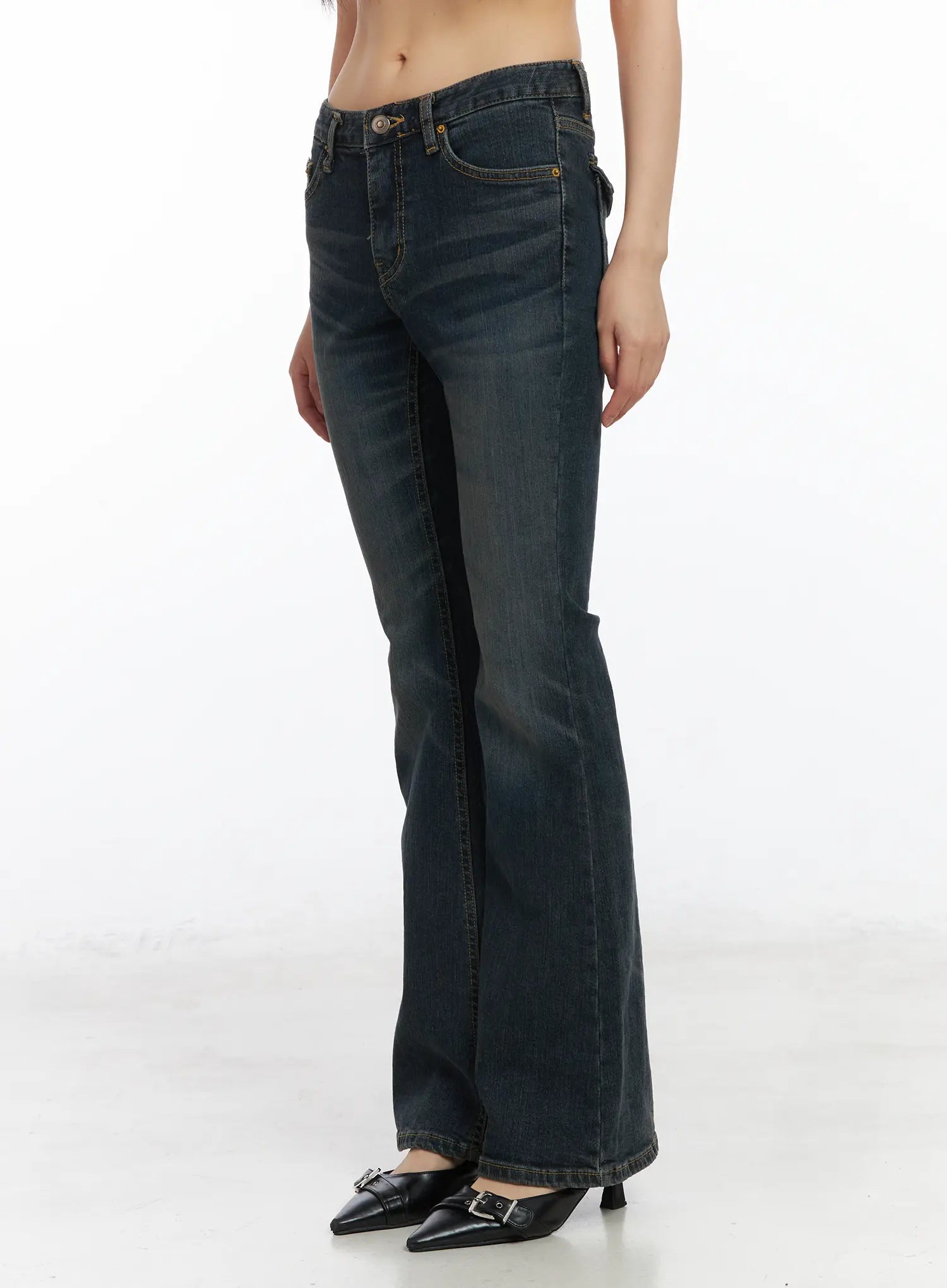 Kai Vintage Washed Flare Jeans CD515 in dark indigo, side-front view on model from waist down, low-rise waistband and front pocket detail visible, flared leg, with black kitten-heel mules.