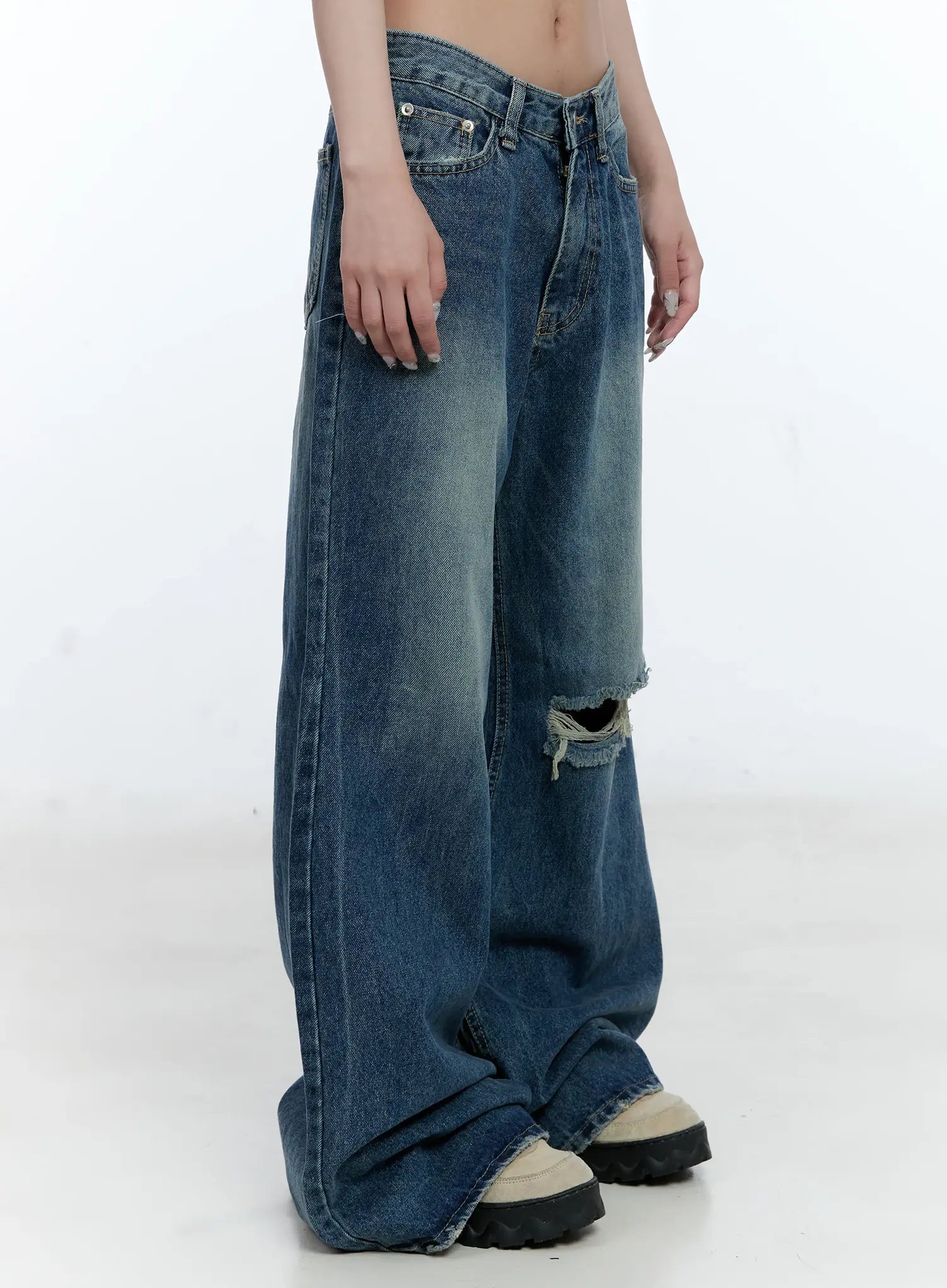 Gabi Distressed Semi-Flared Denim Jeans CG501 in dark blue, close side view on model, emphasizing low-rise waist, knee destroyed hole, washed gradient, and wide flared hem pooling.