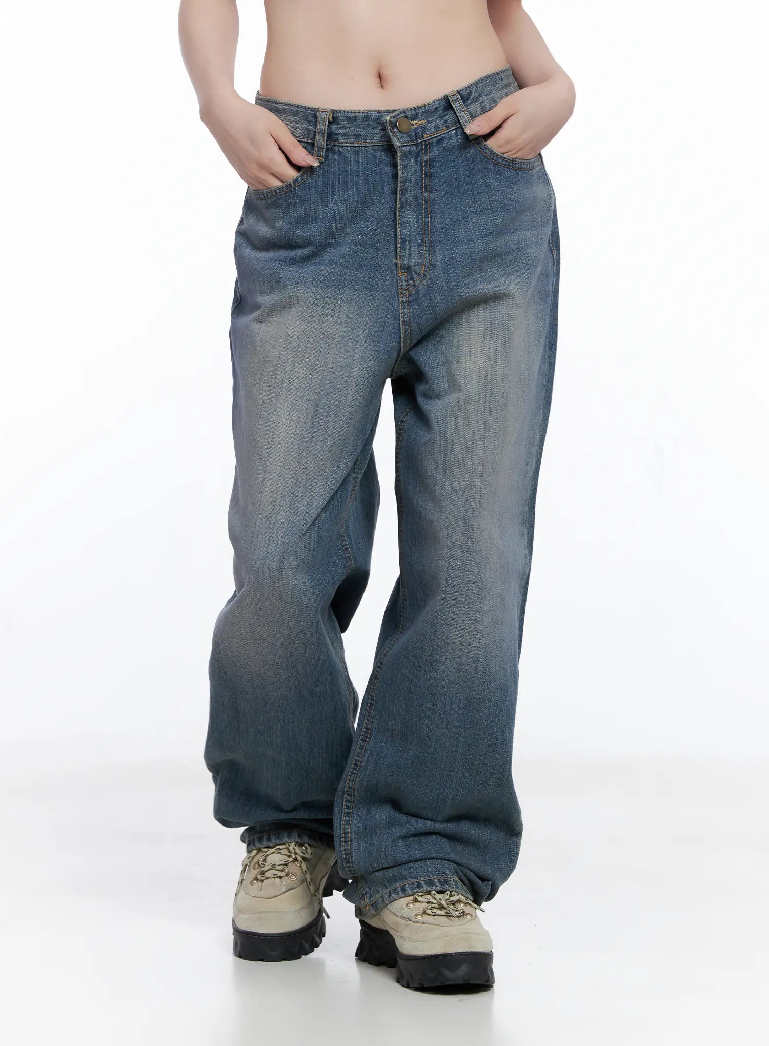Lala Wide Leg Vintage Washed Jeans CG529 in blue, front mid-shot on model with hands in pockets, low-rise fit, wide-leg cotton denim with uneven vintage fade, worn with chunky sneakers.