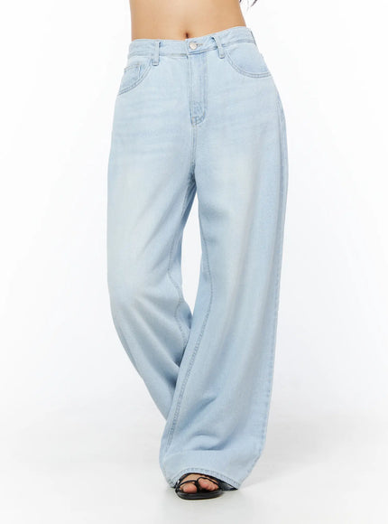 Rina Washed Wide-Leg Jeans CU522 in light blue, angled front view on model (waist-down), relaxed wide-leg drape with subtle washed fade, paired with black sandals.