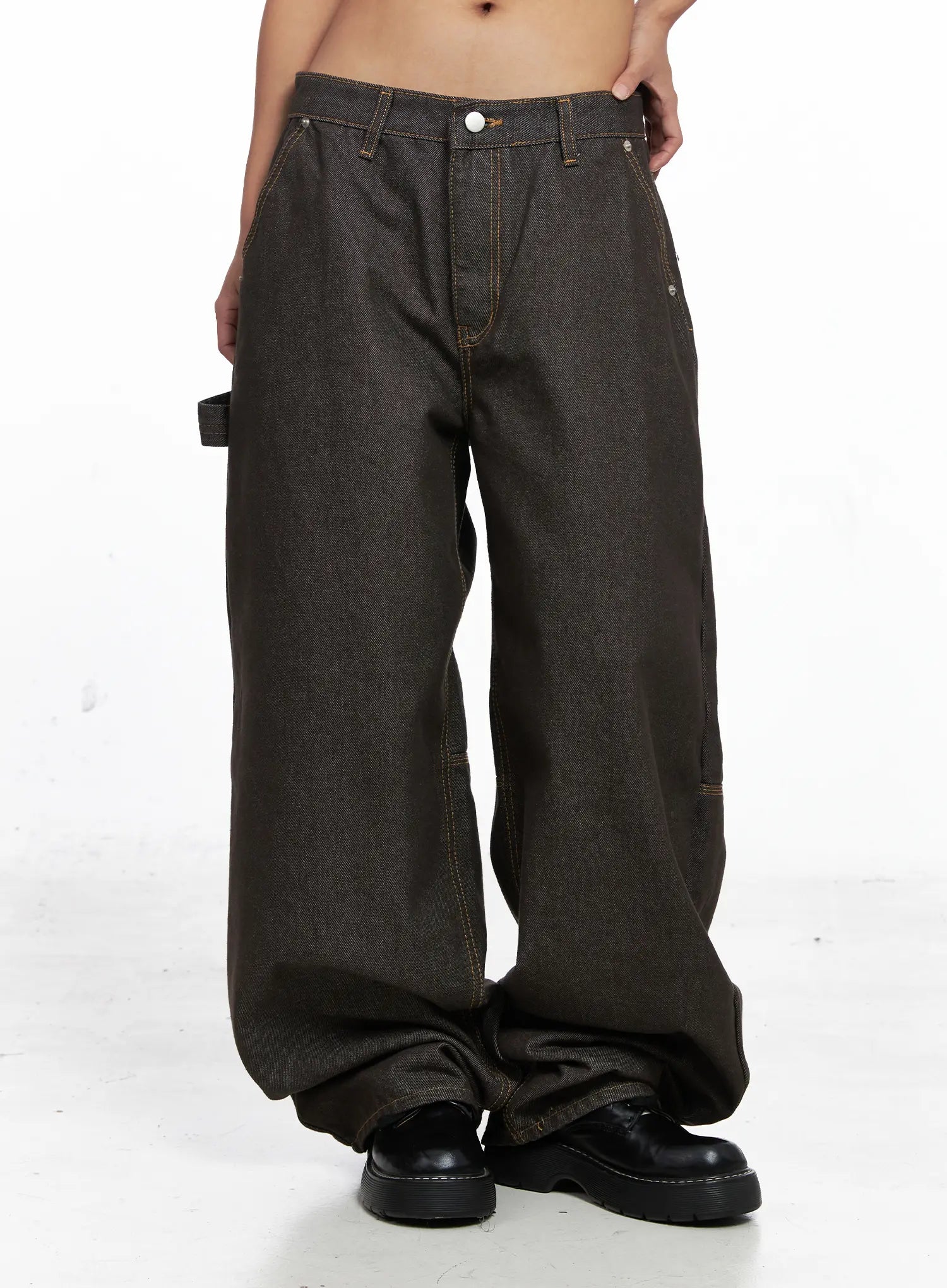 Oaklyn Non-Fade Wide-Leg Jeans CO513 in dark brown, front thigh-to-hem close-up on model, low-rise button fly, contrast orange topstitching, carpenter loop, and pooling wide-leg hem over black shoes.