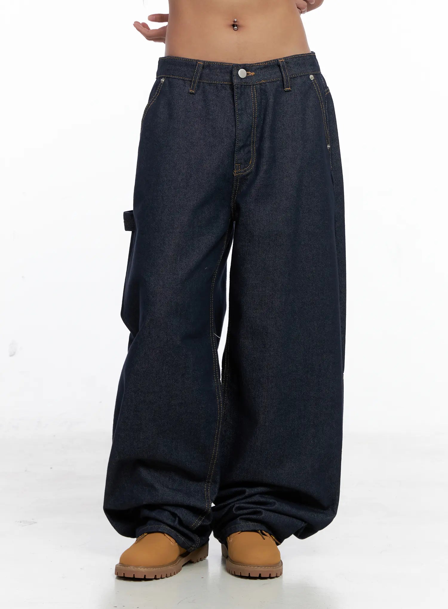 Relaxed Fit Dark Denim Jeans CS522 in dark blue, front three-quarter view on model, balloon wide leg pooling at hem, low rise, side carpenter pocket strap, contrast stitching, tan boots.
