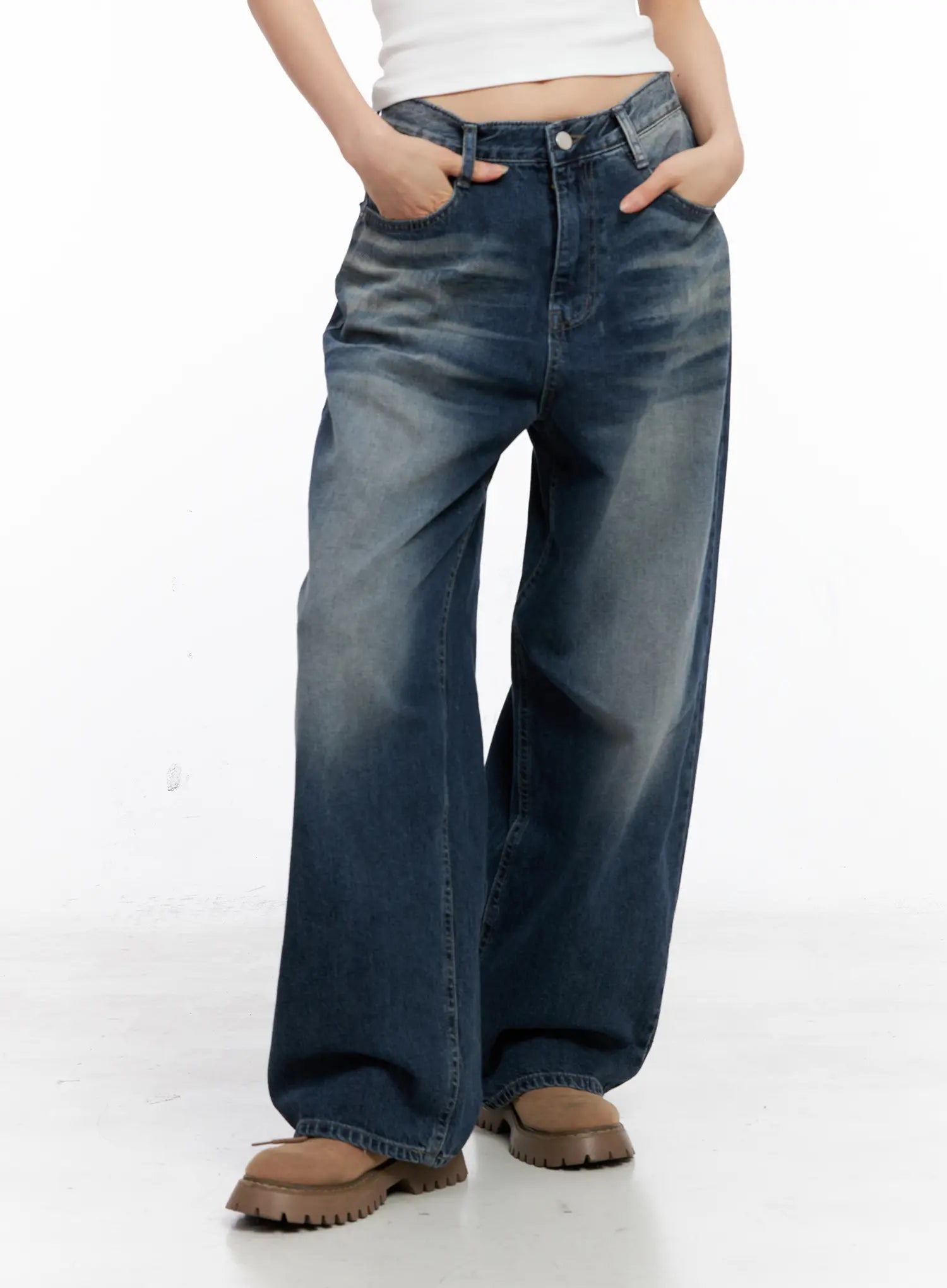 Aisha Washed Baggy Jeans CC1109 in mid blue, front lower-body shot on model with hands in pockets, showcasing wide-leg drape, washed cotton texture, and long inseam with chunky boots.