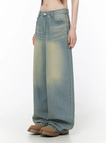 Rain Vintage Washed Wide Leg Jeans CU519 in light blue, side close-up on model, low-rise waistband, pronounced yellow vintage fade on thigh panel, wide leg draping over chunky boots.