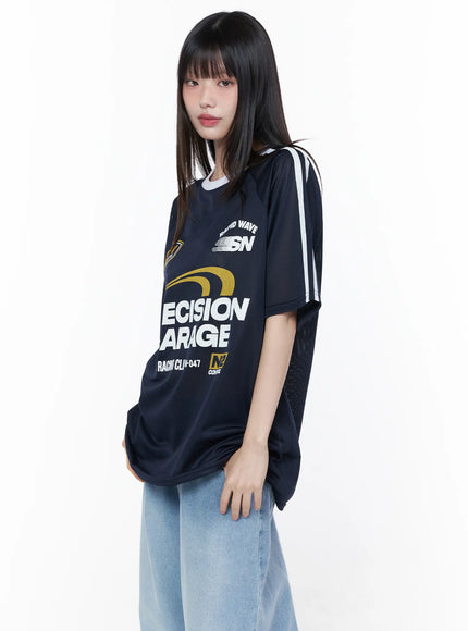 Oversized Sporty Graphic Tee CU519 in dark blue, angled front on model with bangs, semi-sheer mesh fabric with Precision Garage graphic, white sleeve stripes, paired with light blue jeans.