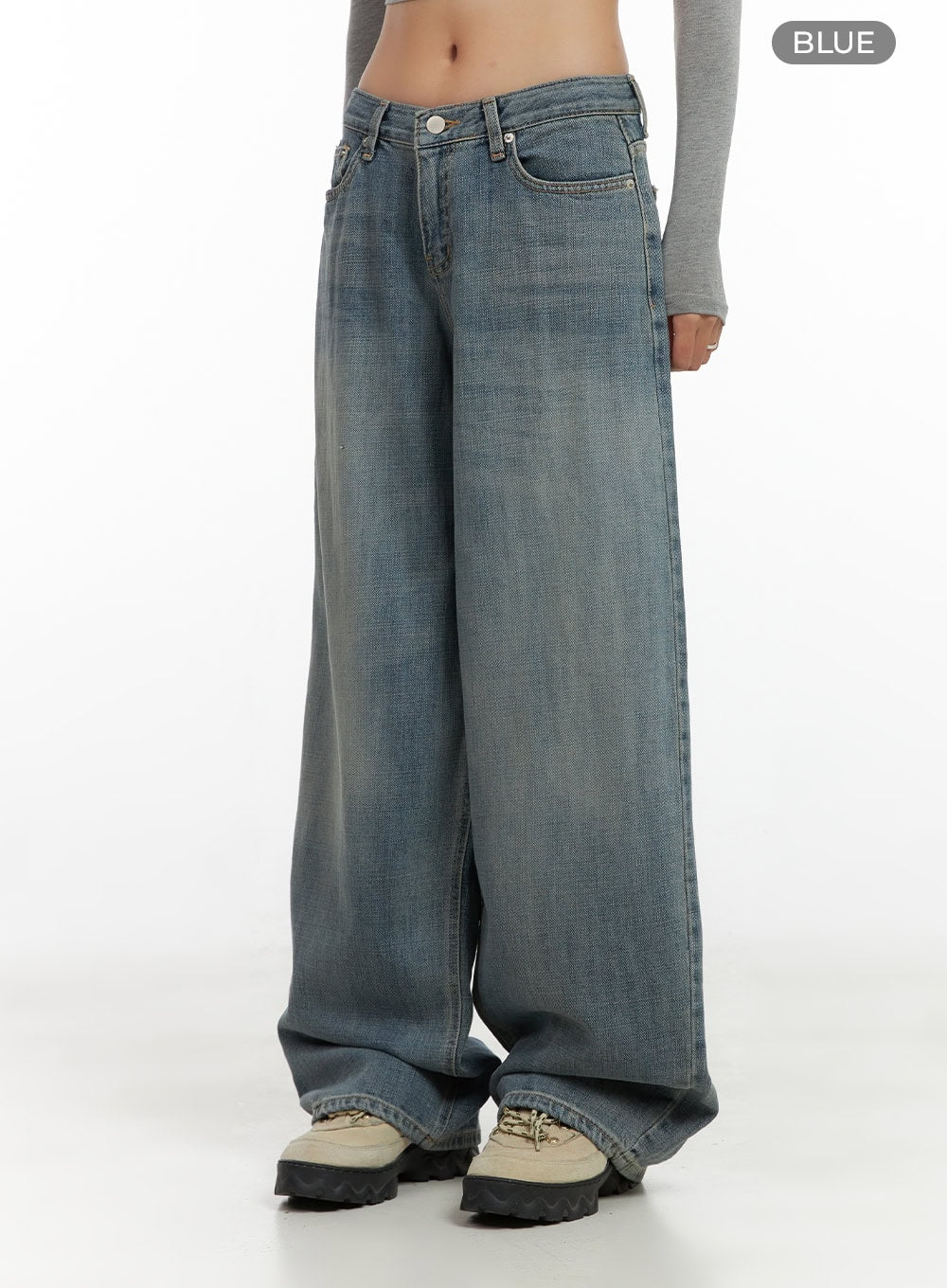 Nadia Washed Low-Waist Baggy Jeans CO424 in blue, front three-quarter close-up on model, color swatch variant shot, V-shaped low waistband and wide-leg washed denim, styled with grey crop top and chunky sneakers.