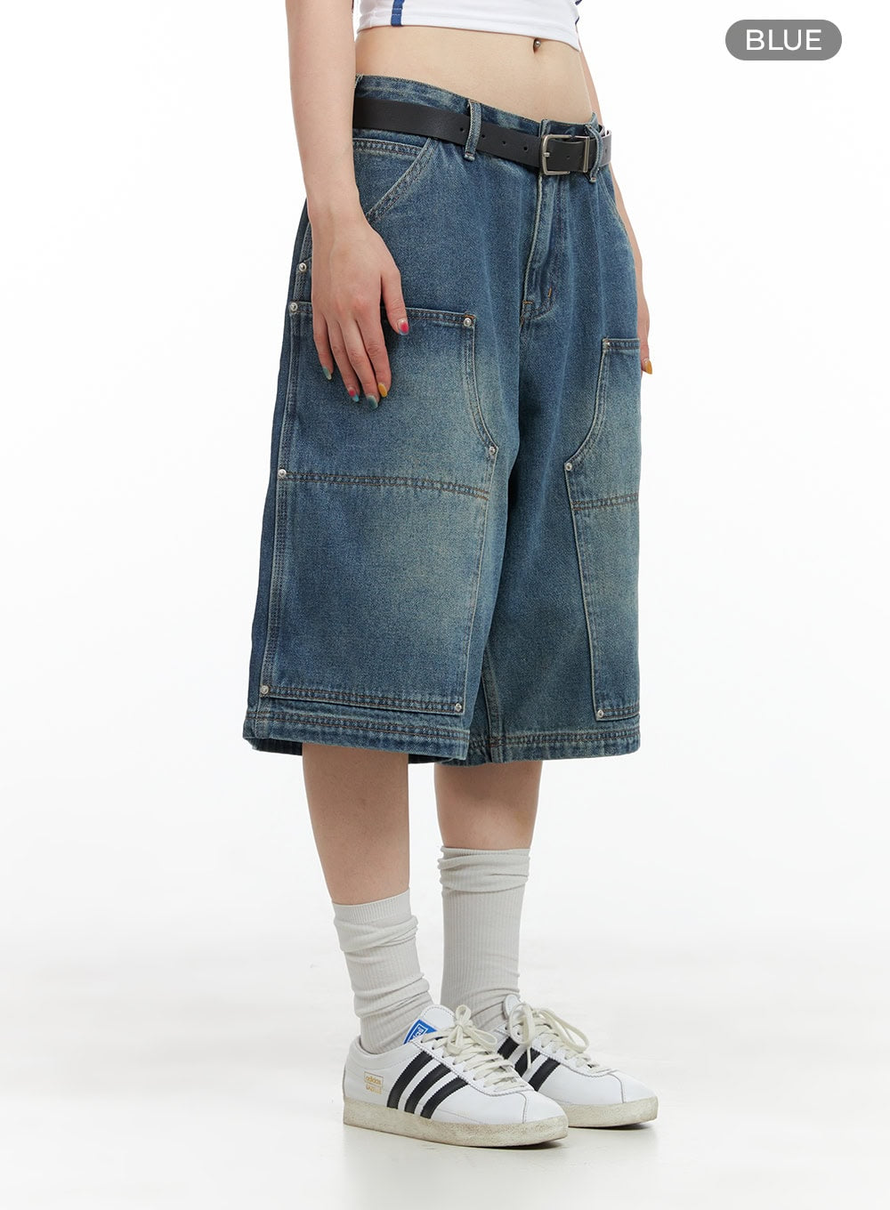 Stud Washed Baggy Jorts (UNISEX) CG408 in blue, side view on model, wide-fit washed denim with stud details and carpenter-style pockets, black belt, and Adidas sneakers.