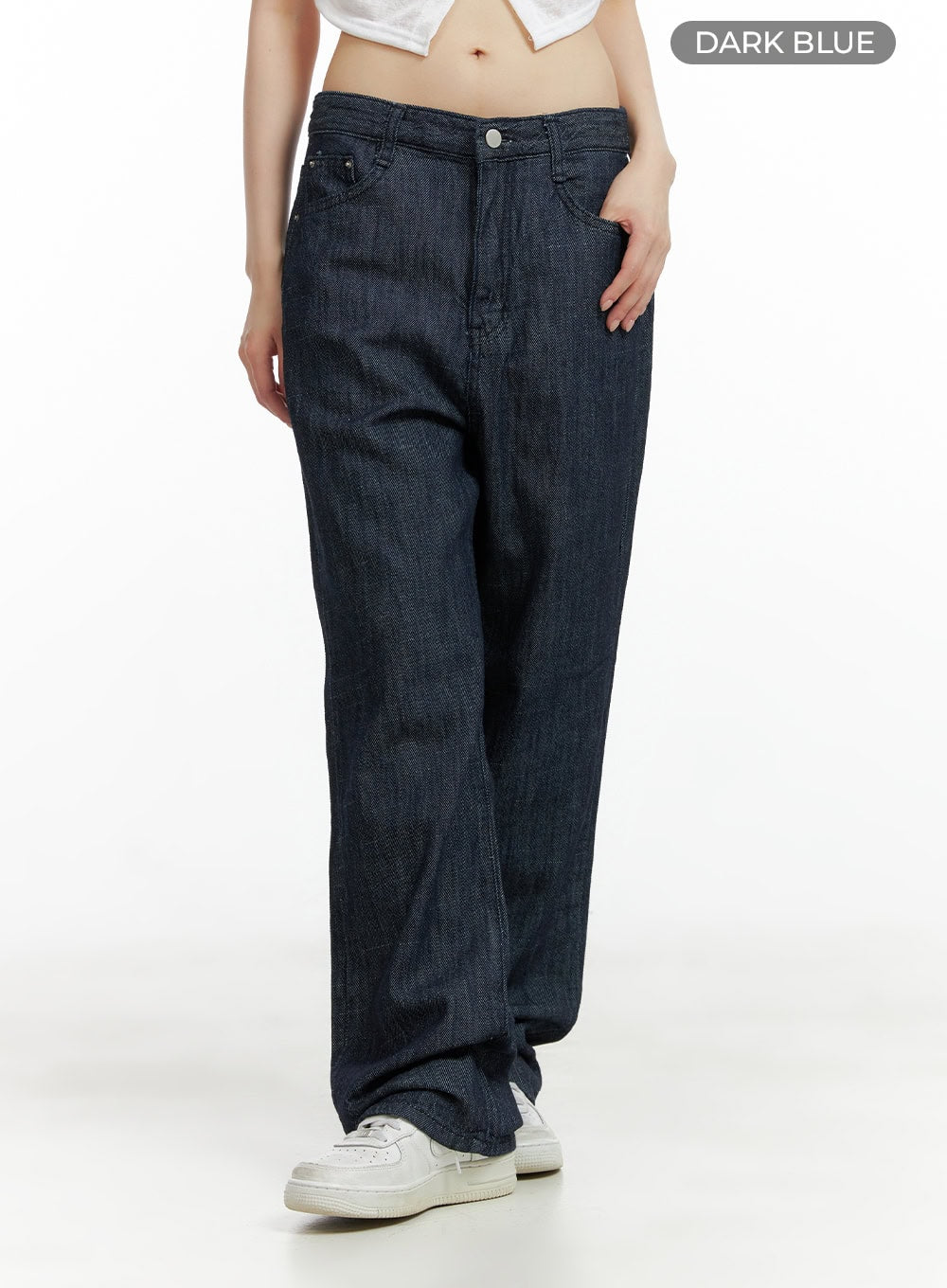 Low Waist Loose Fit Baggy Jeans CL403 in dark blue, front three-quarter shot on model, low-rise five-pocket styling, wide baggy leg denim, hand in pocket, with white sneakers.
