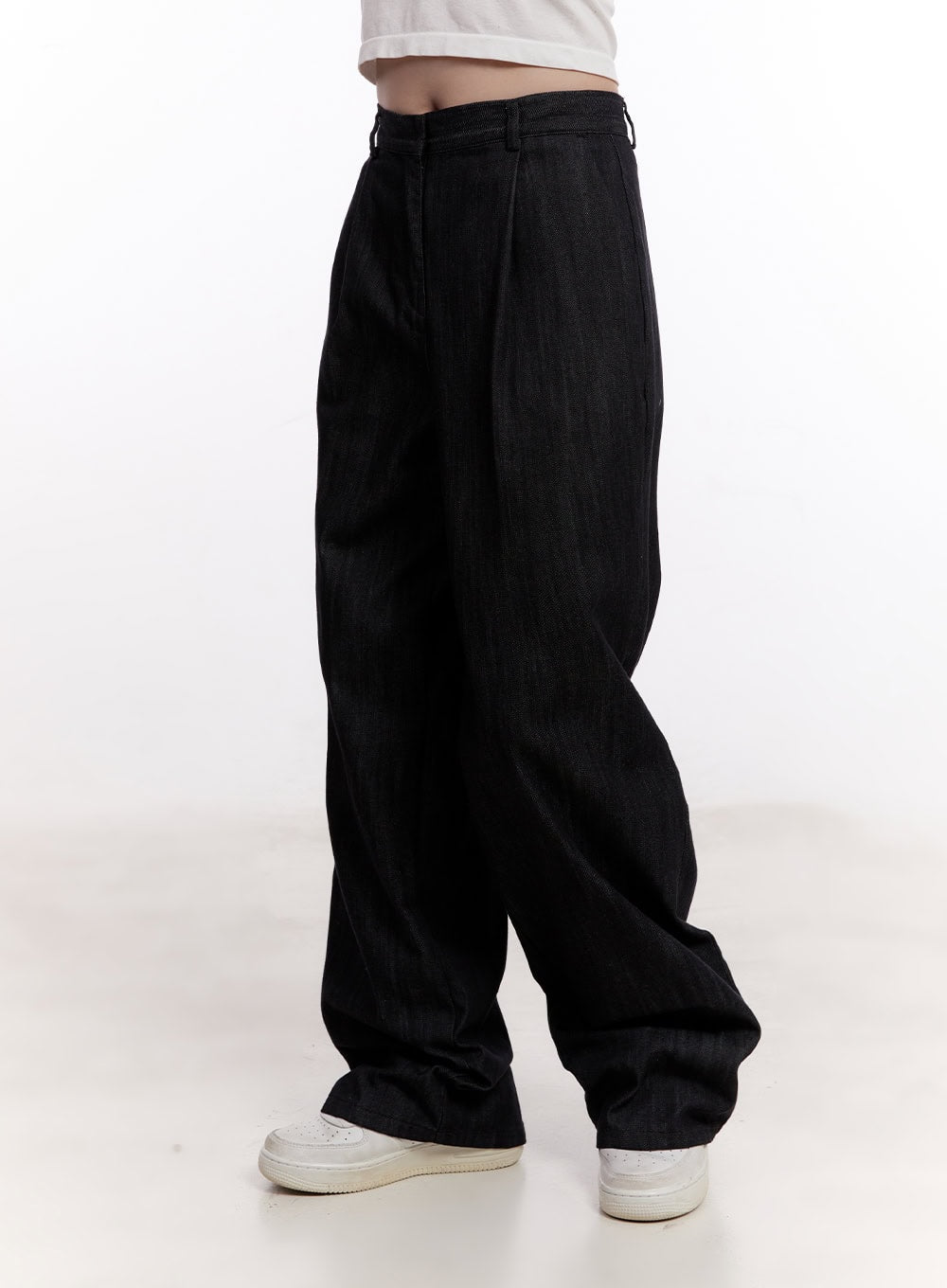 Pintuck Wide-Leg Denim Pants CM527 in black, angled front-side close-up on model, pintuck pleat and high-waist waistband detail, voluminous wide leg, white sneakers.