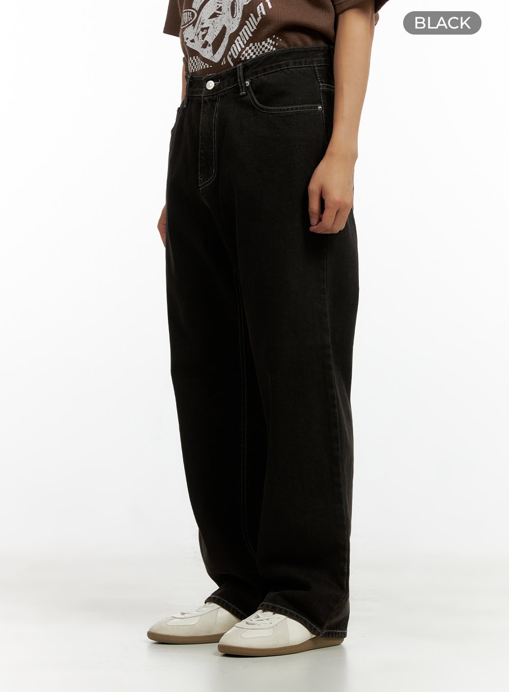 Men's Wide Fit Washed Baggy Jeans CL429 in Black, angled side view from waist down on model, washed baggy denim with contrast stitching detail, color label visible, styled with white sneakers.