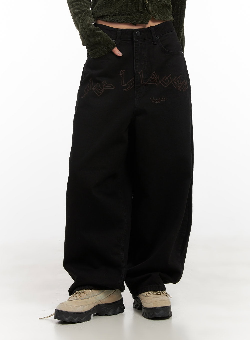 Yasmin Denim Wide Fit Jeans CD413 in black, front waist-to-hem view on model, high-rise waistband with button fly, wide balloon leg, dark lettering print, paired with olive corduroy knit and chunky sneakers.
