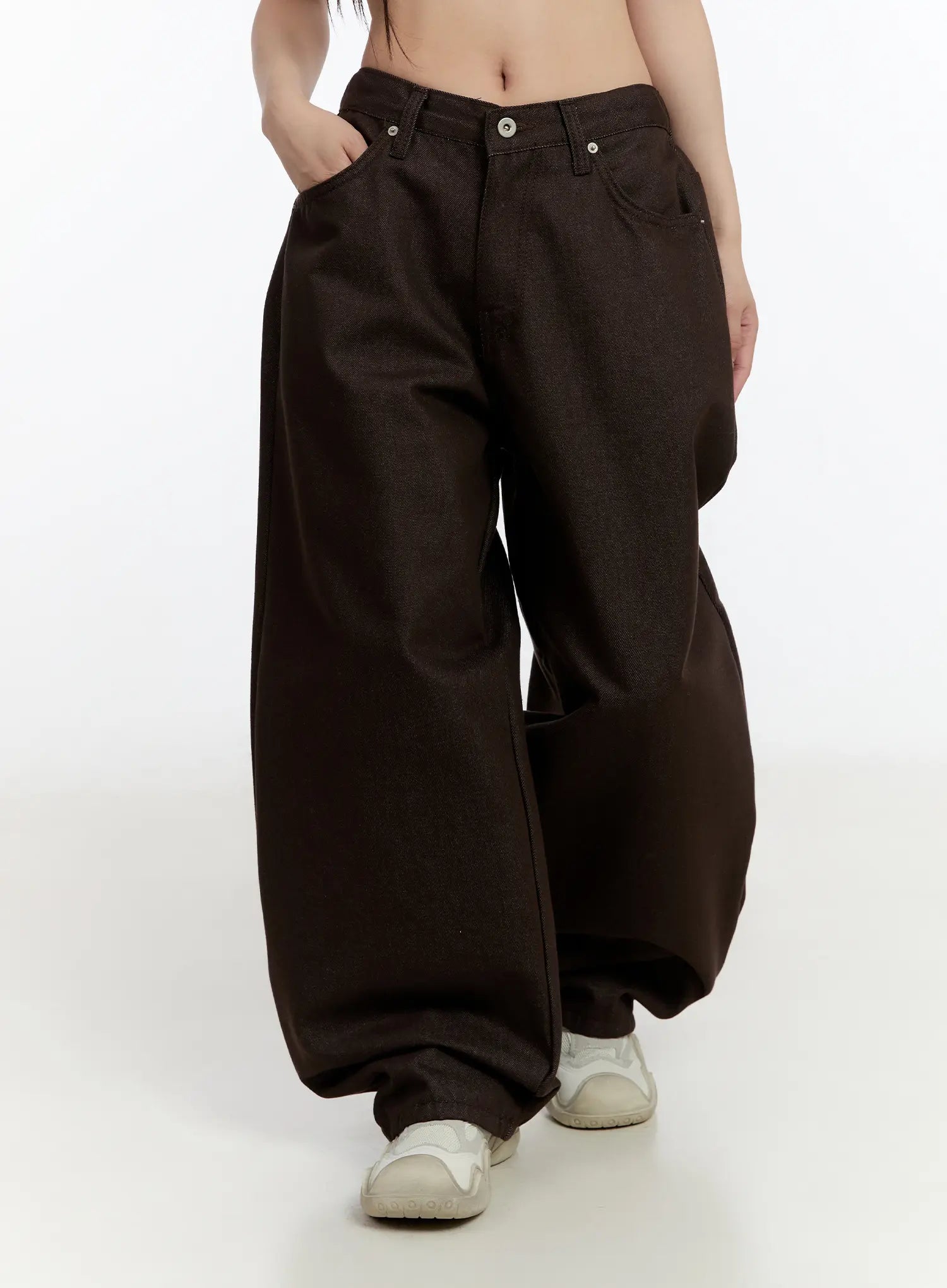 Emely Wide Leg Jeans CN524 in dark brown, front mid-shot on model in motion, low-rise button waist, exaggerated balloon wide-leg denim, hand in pocket, paired with white sneakers.