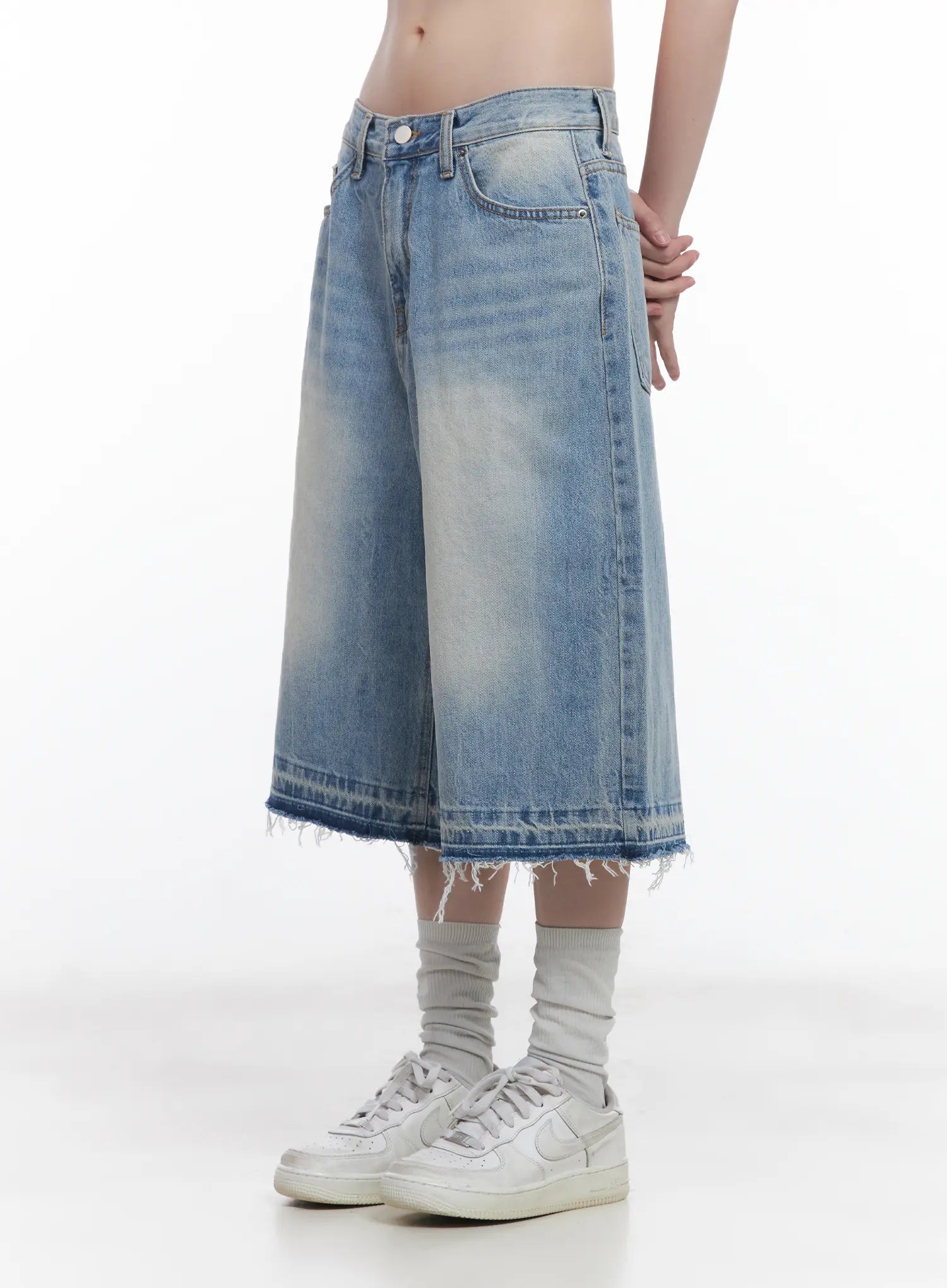 Light Wash Vintage Jorts CU519 in blue, side full-length close-up on model, low-waist wide-leg silhouette, light vintage wash with contrast frayed hem, white sneakers and grey socks.