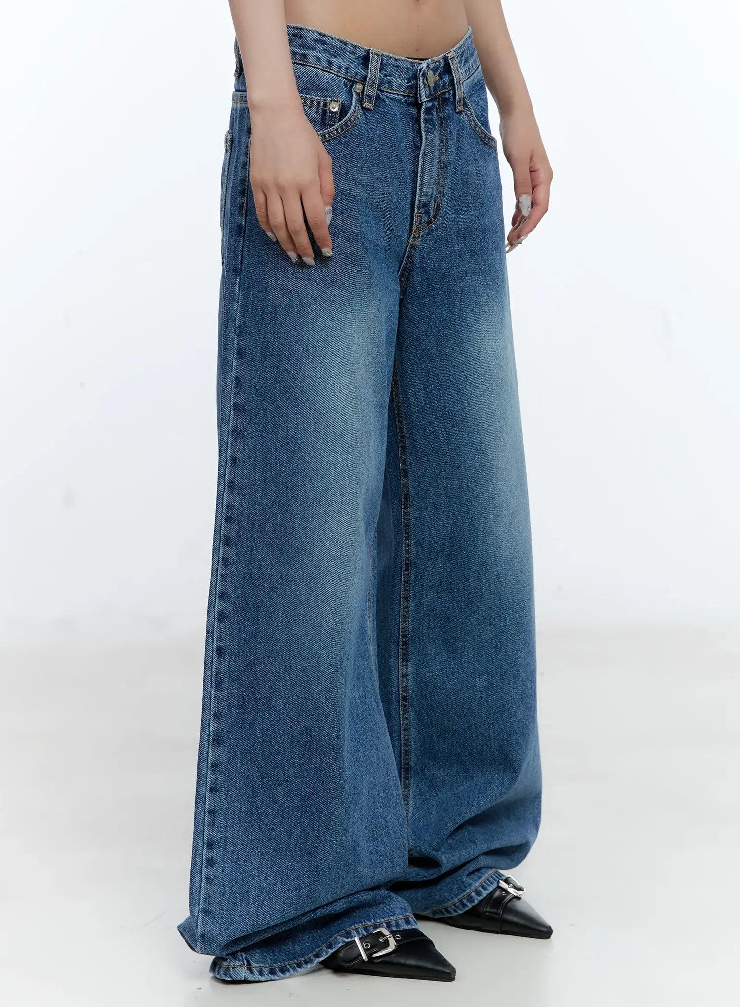 Dahye Washed Relaxed-Fit Denim Jeans CL530 in blue, side angle close-up on model, wide-leg drape from hip to floor-pooling hem, washed fading detail, cotton denim with black heeled shoes.