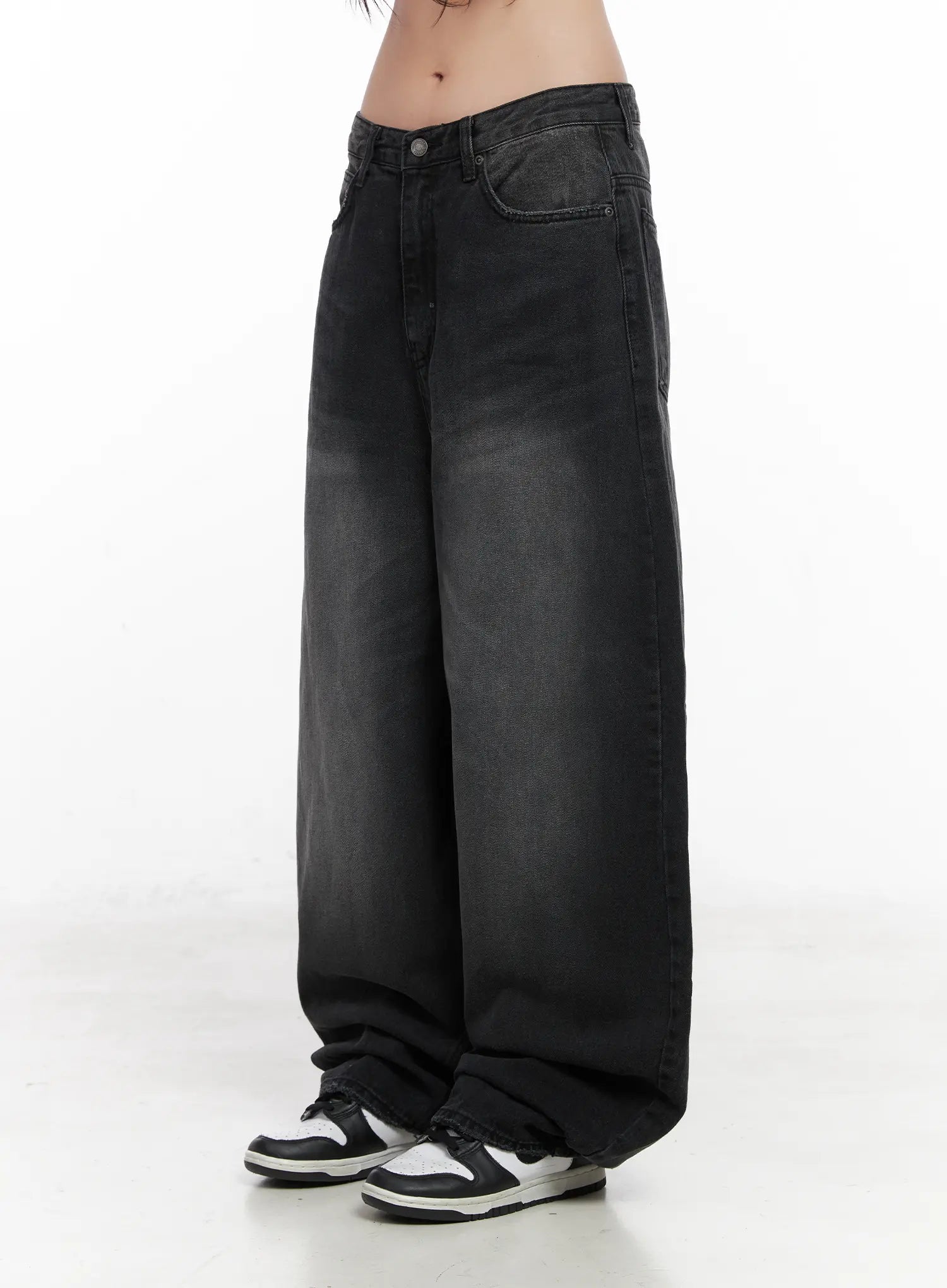 Yuji Dark-Washed Baggy Jeans CN513 in black, side product shot from waist down on model, clean side view of low-rise waist and extremely wide-leg cotton denim with faded wash, hem pooling over sneakers.