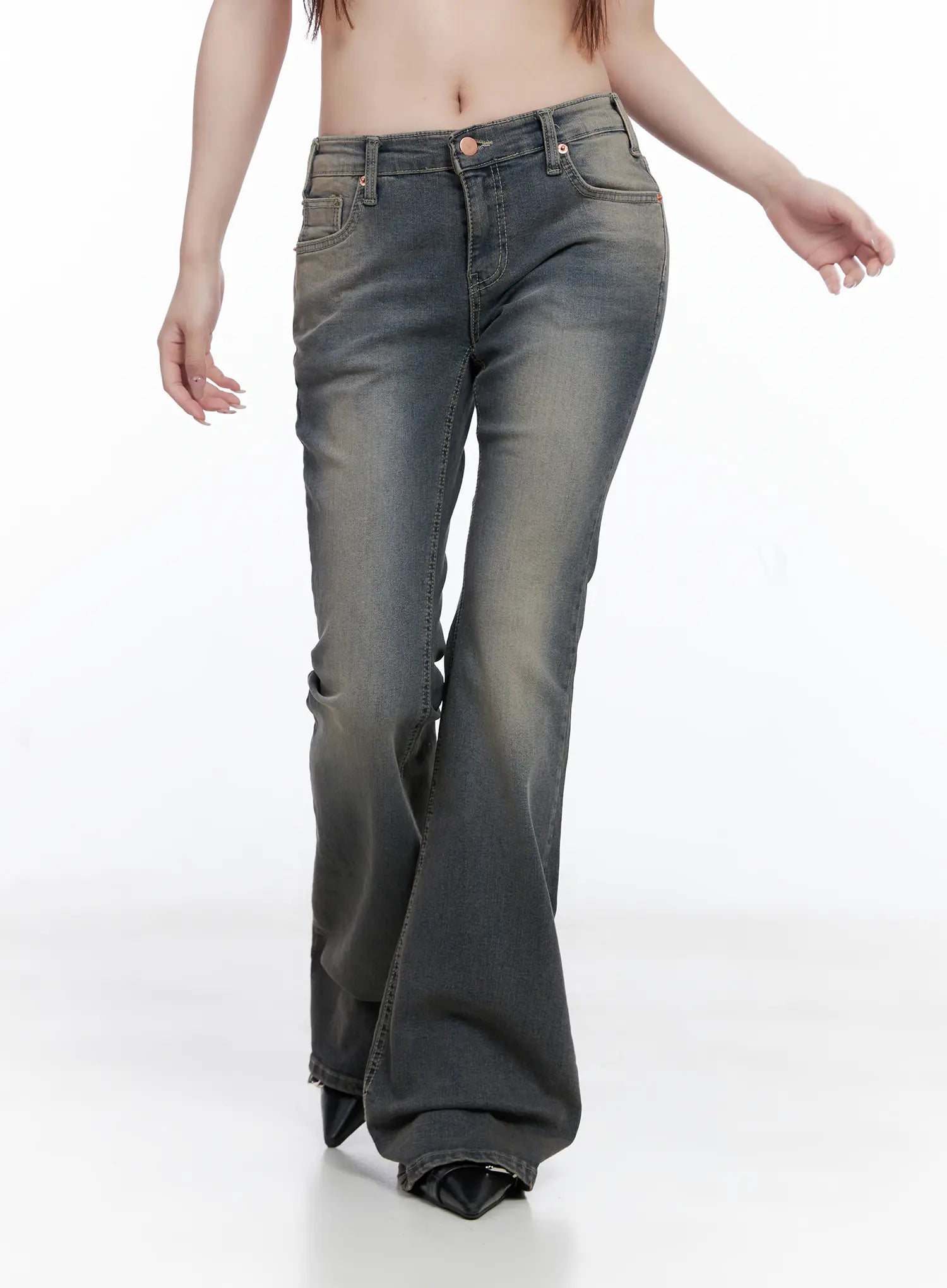 Sumin Low-Rise Flare Hip Pad Jeans CG529 in gray, front mid-shot on model walking, washed gradient denim, low-rise waistband with rose gold rivets, flared long hem.